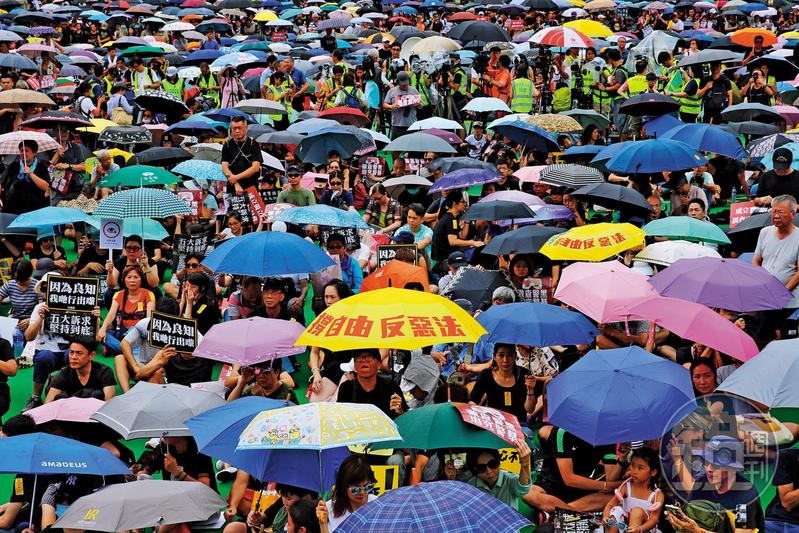 818集會當天下起暴雨,上街民眾撐起傘繼續遊行。(本刊資料照)