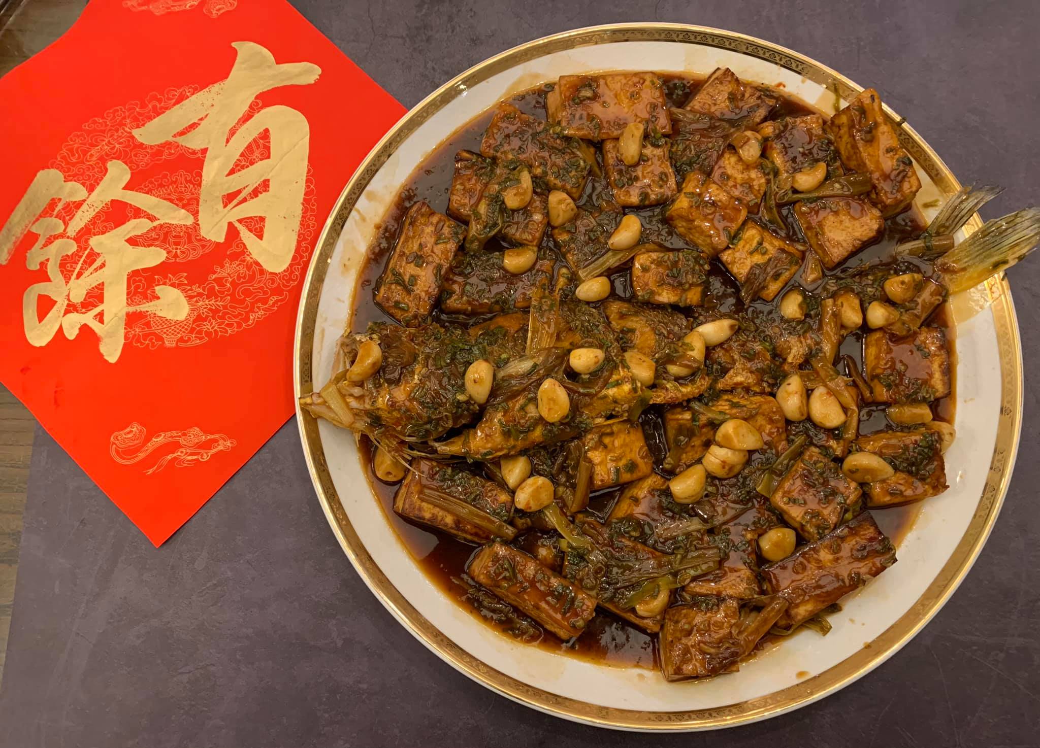 家傳口味的「豆腐燒黃魚」上桌，現在有拍照概念，放了春節裝飾。用45公分的大盤盛裝，可見此魚之大。