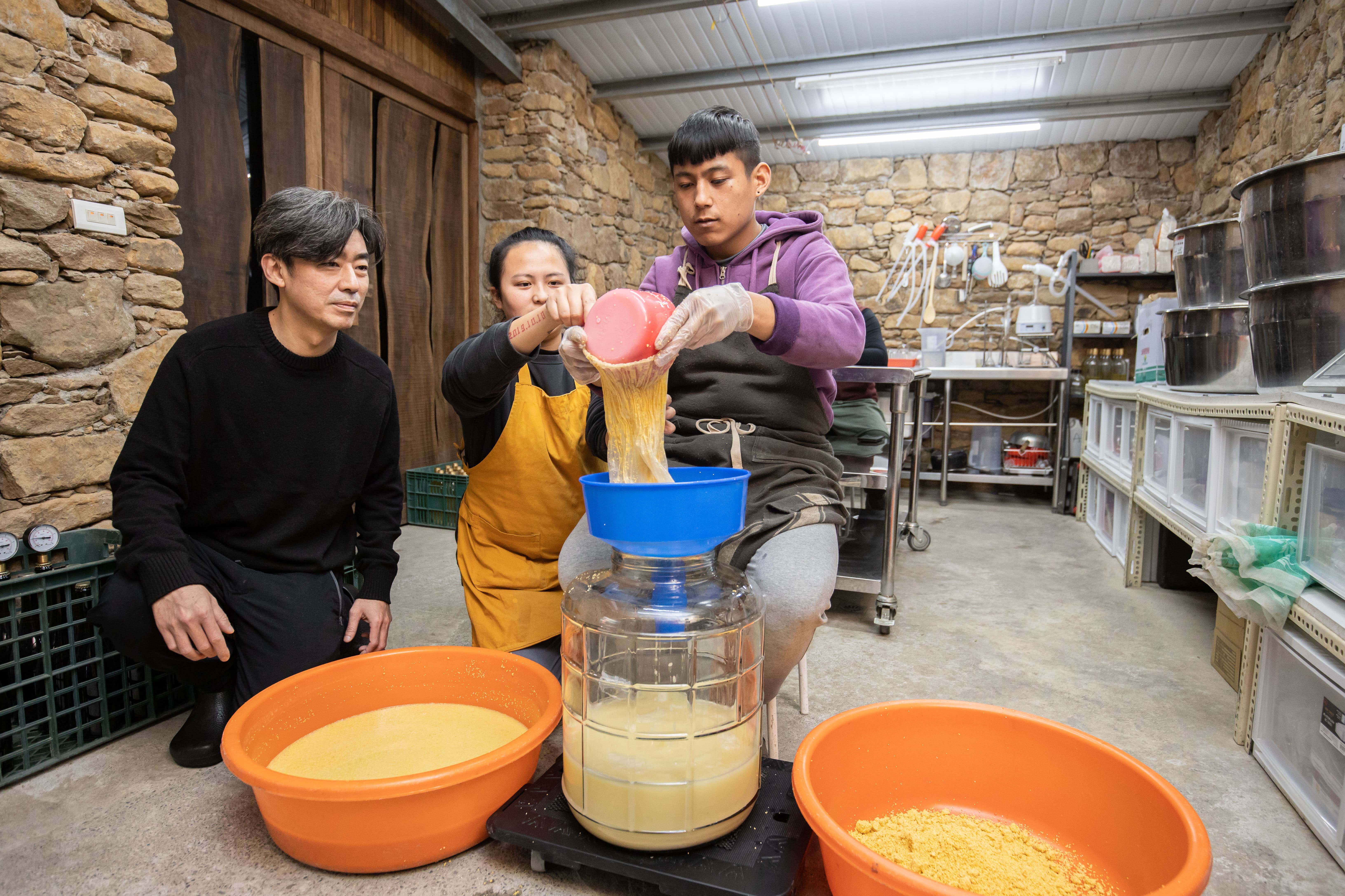 歐子豪與部落釀酒師妙惠、族人,一同進行瀝酒程序。
