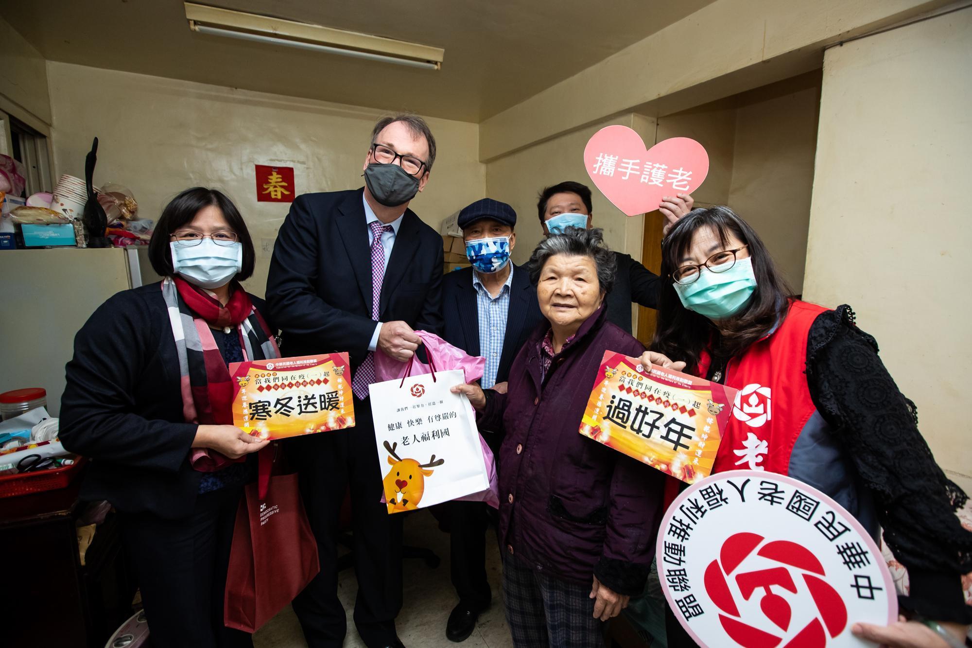 董事長馬智歐（左2）與總經理張成發（後排右1）積極融入台灣社會，過年前親赴北市萬華福民平宅贈送年菜。（美歐亞綠能提供）