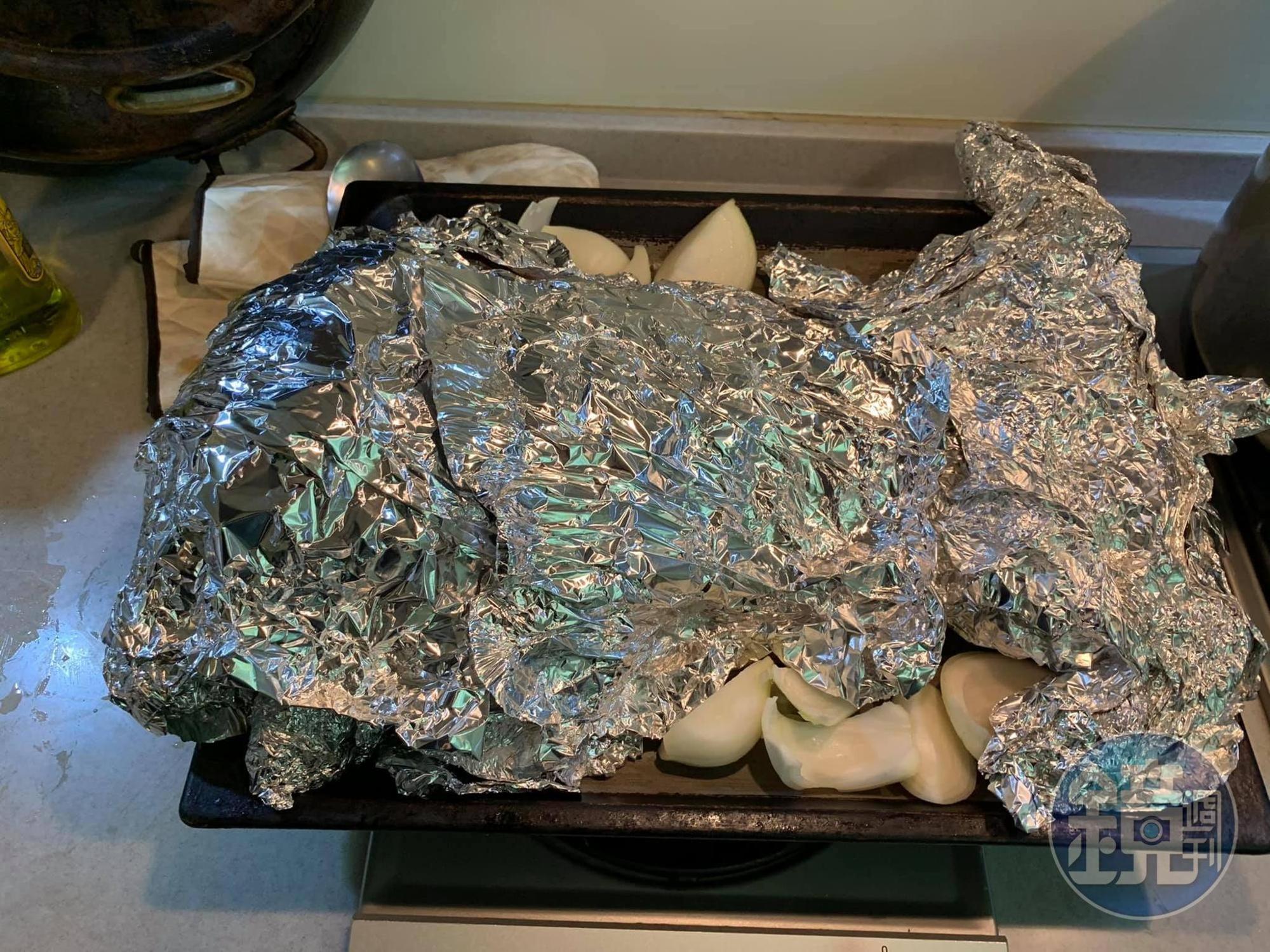 烤盤鋪上洋蔥，放上乳豬，包裹住鋁箔紙。