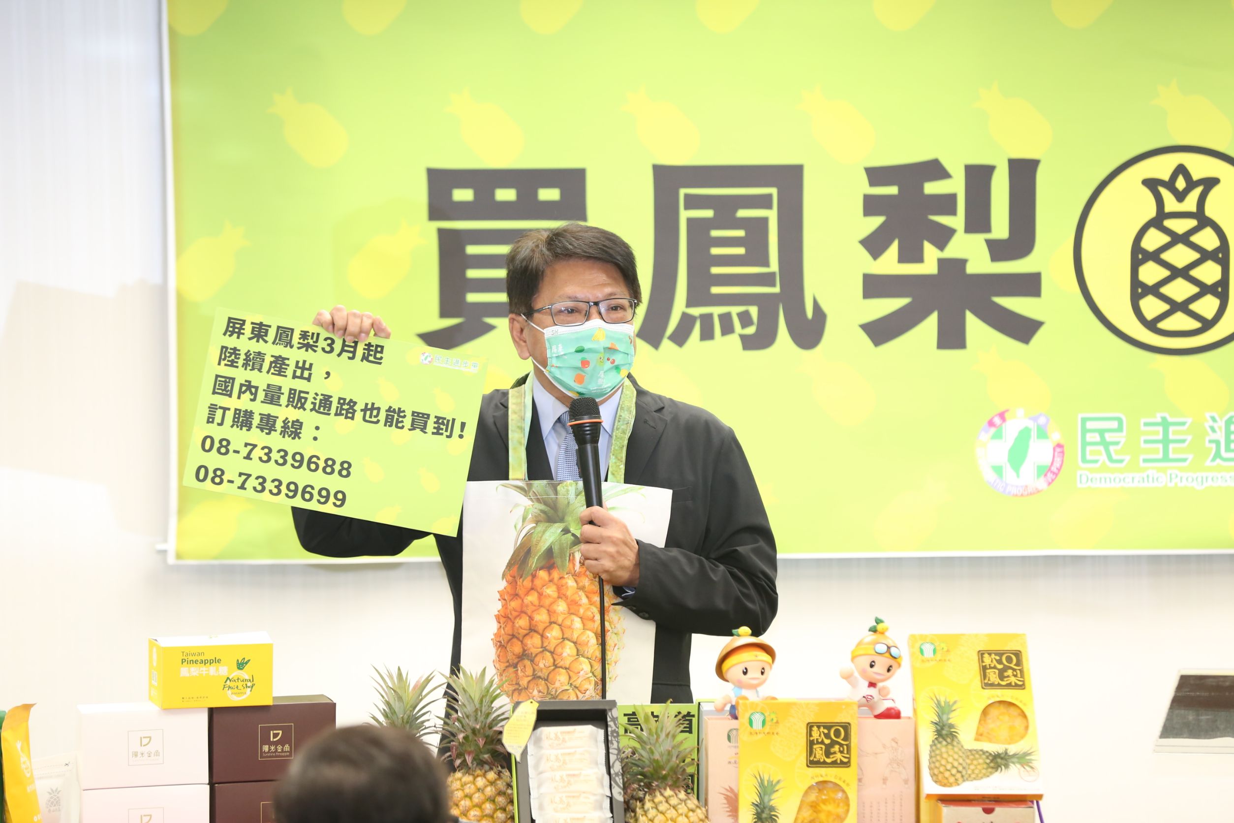 屏東縣長潘孟安將印有鳳梨圖樣的購物袋掛在胸前,化身購物專家推銷屏東鳳梨產品。
