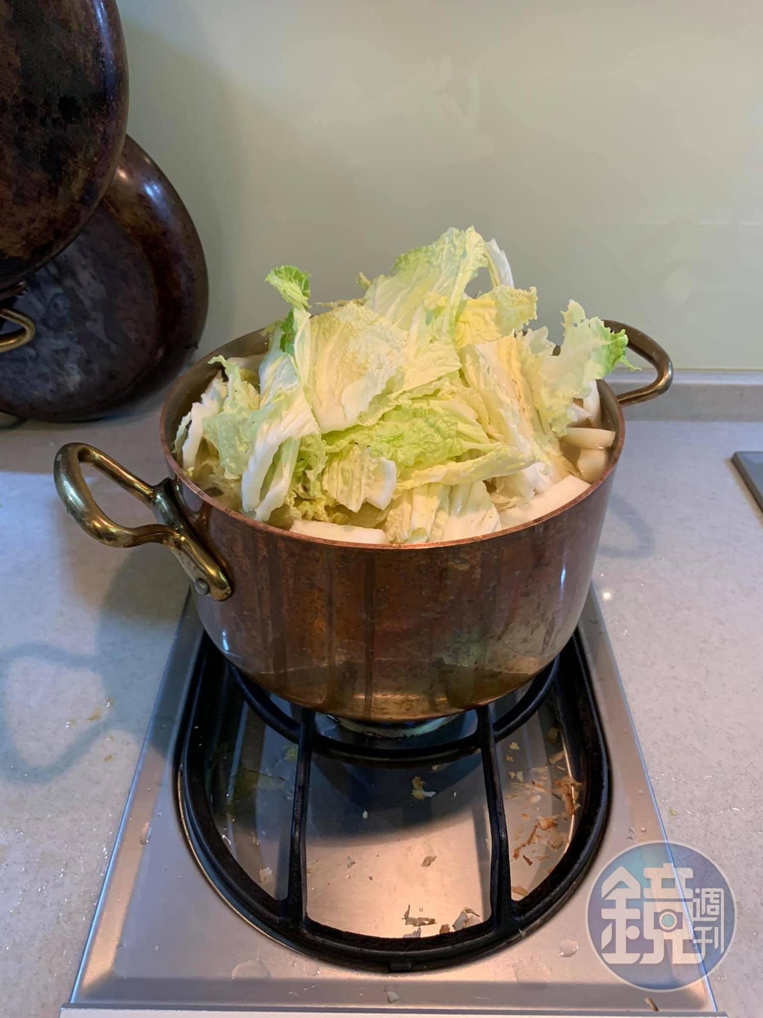把炒軟的蔬菜放入大銅鍋中，加入大白菜與泡香菇的水。