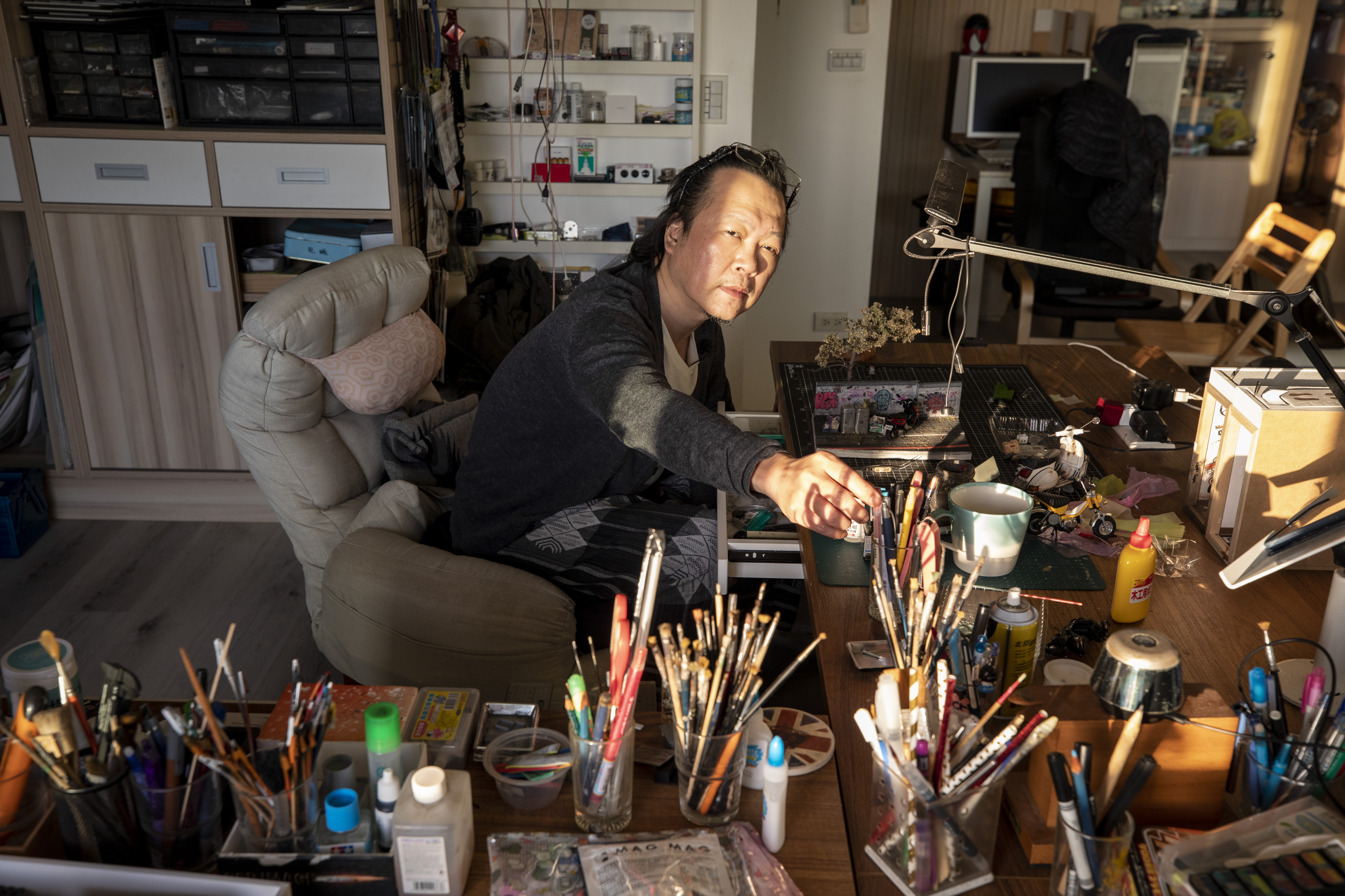 鄭鴻展的工作桌充滿各類工具與微縮物件，因為平面與室內裝修設計的工作歷練，讓他得以掌握各種材質的運用。