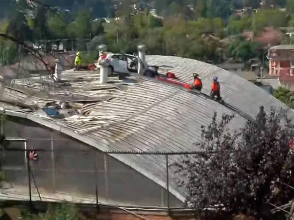 智利一輛汽車失控飛出山路,意外墜毀於一旁建築屋頂。(翻攝自T13 Youtube頻道)