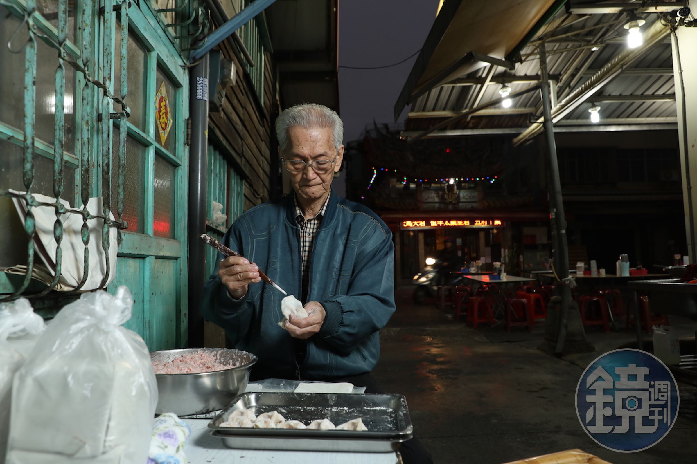 創始人許秉乾（黑乾）在矮房子旁靜靜地包著餛飩，彷彿時間緩下，日子靜好。