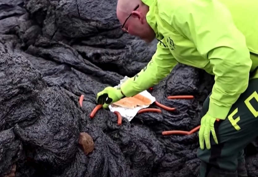 冰島日前發生火山噴發，就有大膽的民眾直接在冷卻中的熔岩上烤熱狗。（翻攝自《CBS Miami》YouTube）