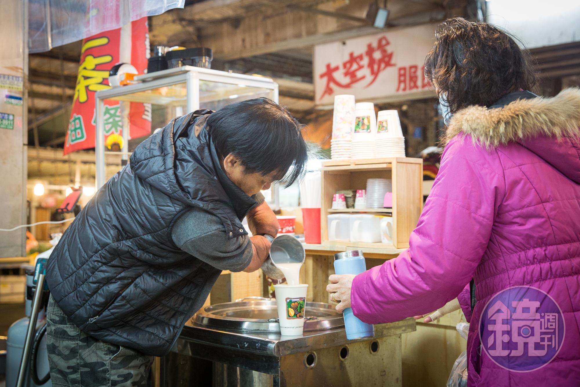林建民（左）雖然截肢，但用鋼杯舀杏仁湯、裝杯都難不倒他。