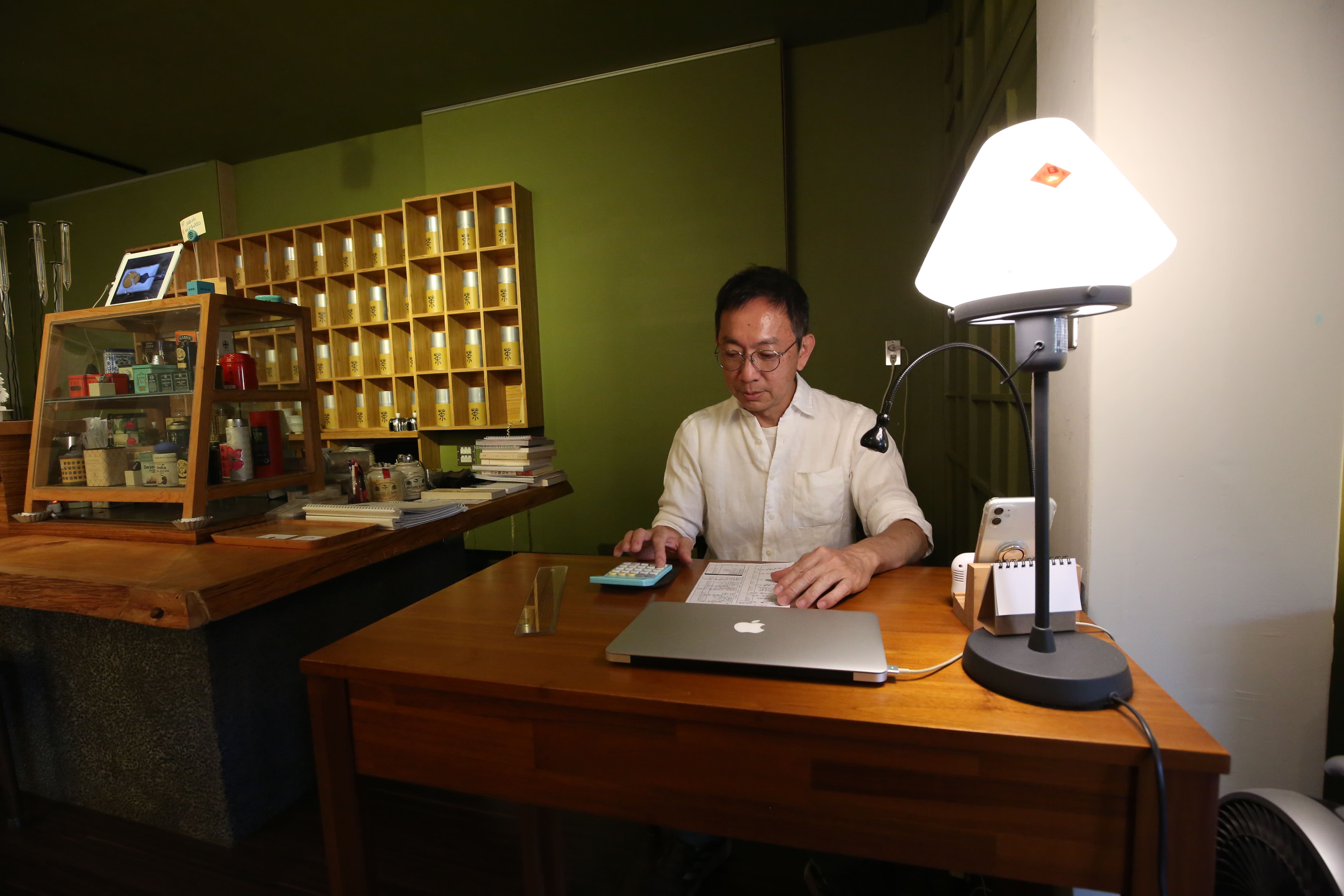 老闆杜宗康坐在自己的小事務桌，後面來自各地的紅茶宛如聯合國。