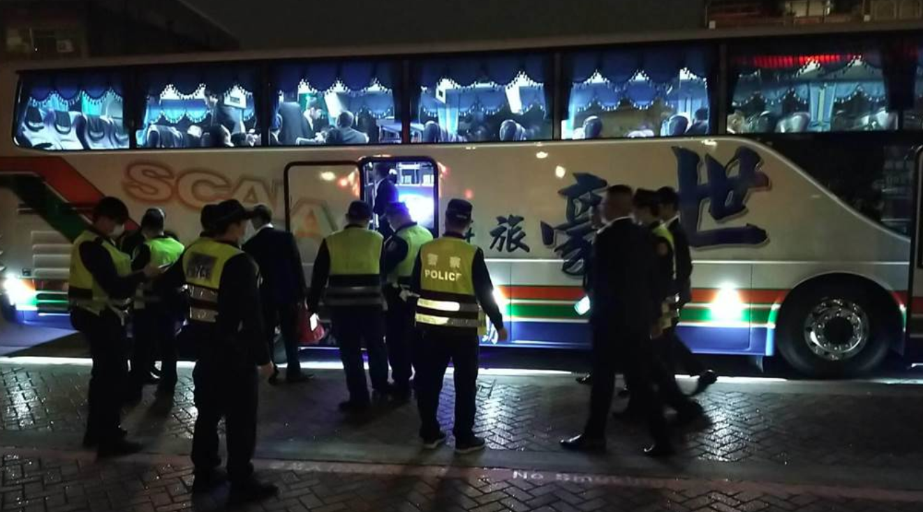 警方查獲30名幫眾上遊覽車準備南下,進行盤查抄錄身分、清查違禁品。(翻攝畫面)