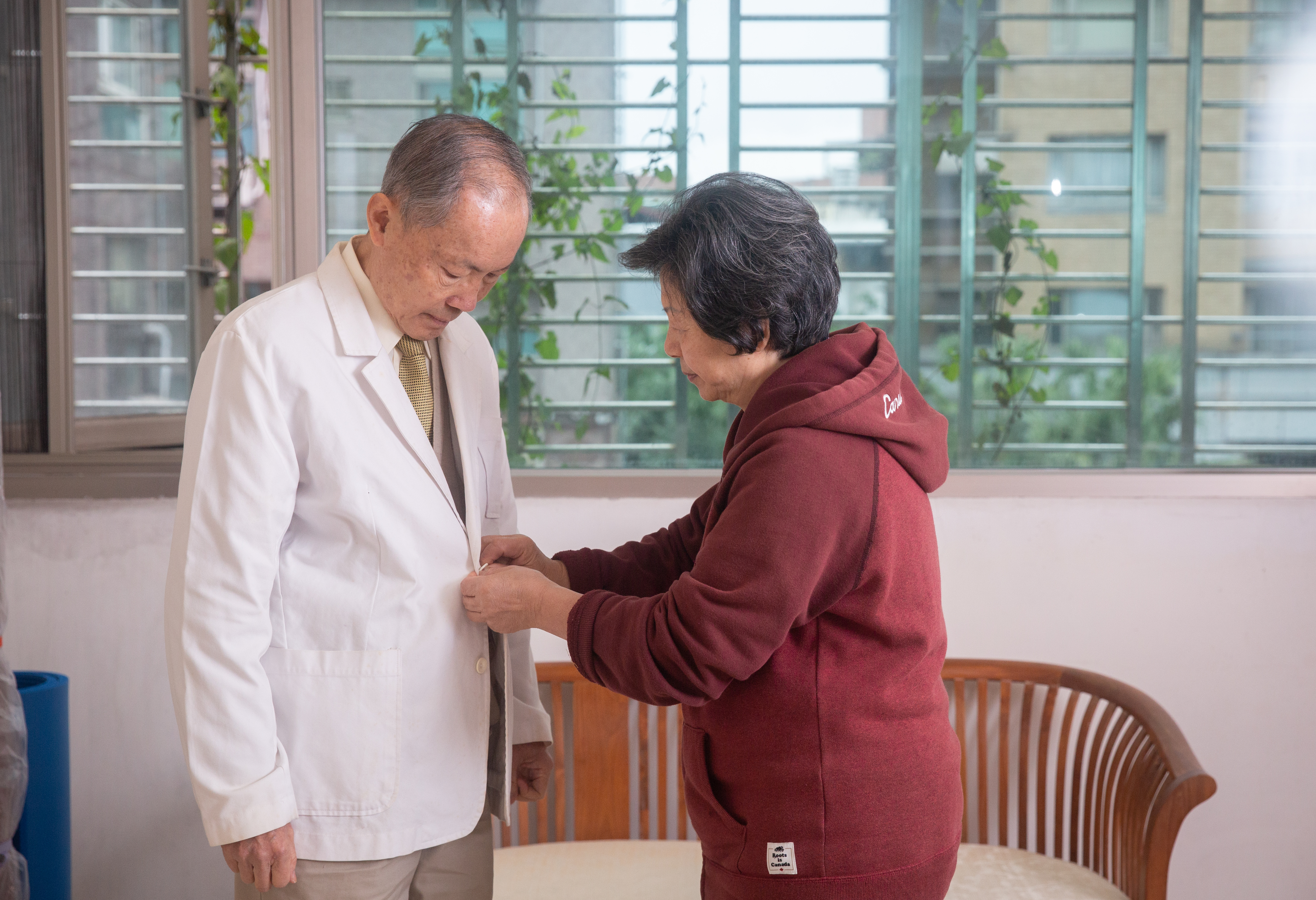 李宜殷（右）幫周經凱穿上兒子的醫師袍。她說，假設此生未能平反，要讓兒子繼續做。