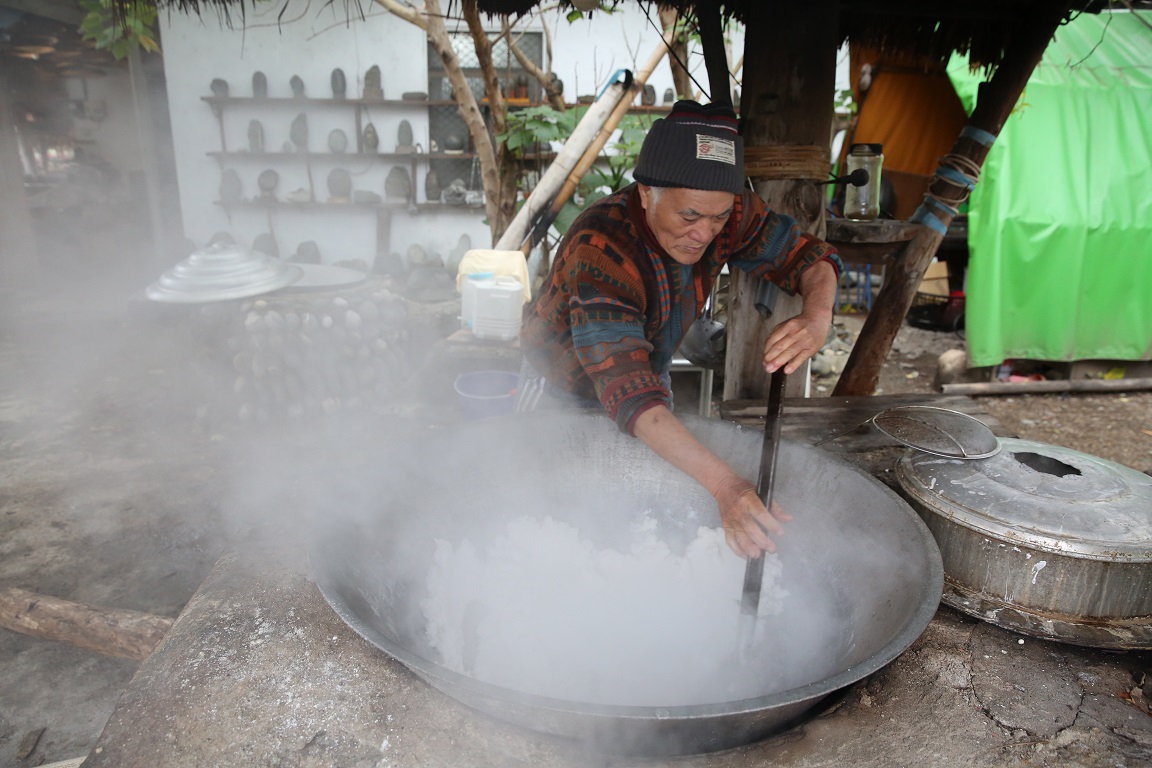 蔡爺爺不斷在大鍋內翻炒，白煙竄出，非常費工。