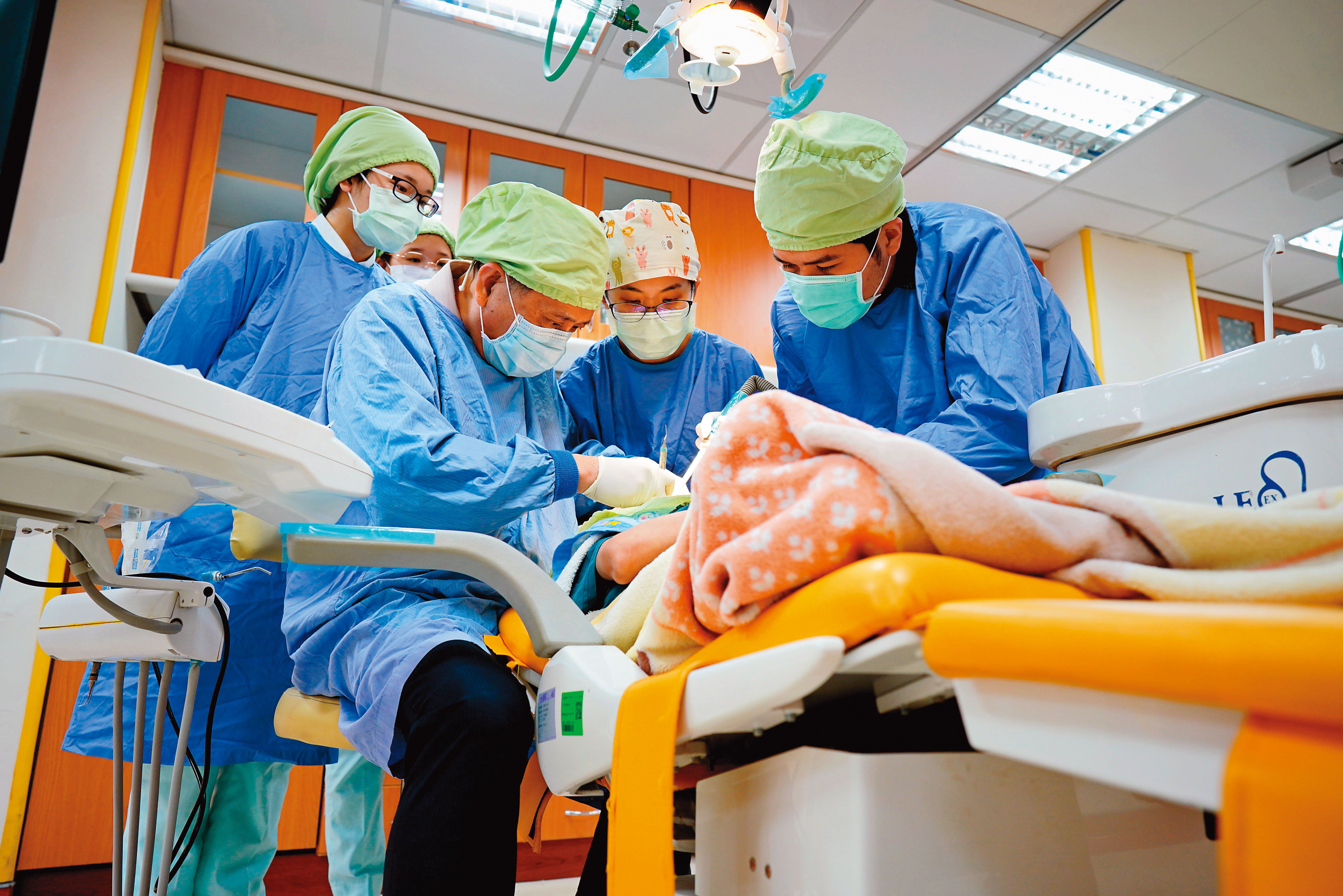 這是高醫特殊需求牙科門診現場，除了牙醫之外，還要多名牙科助理在旁協助。人力需求與看診時間都比一般牙科高。