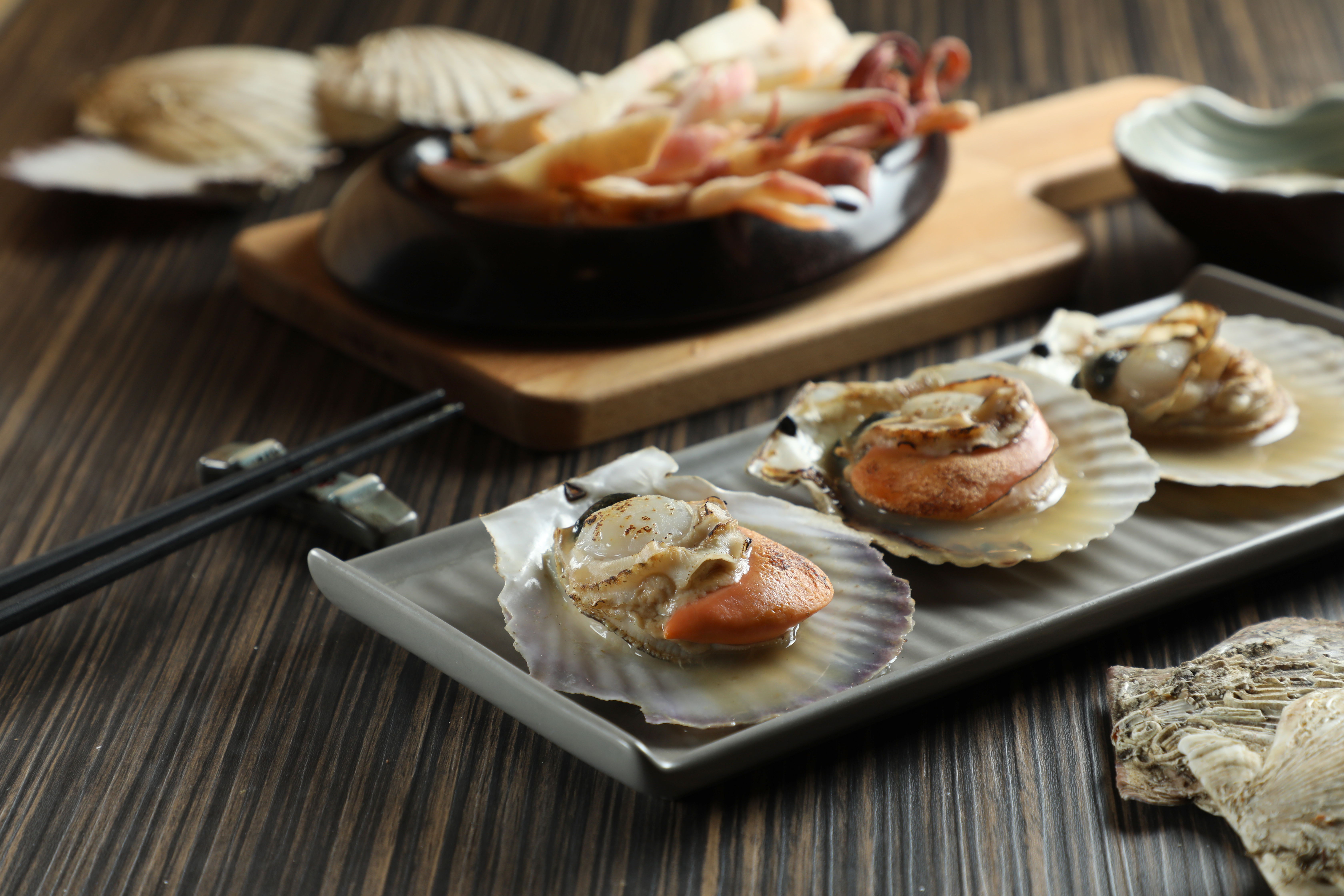 北海道的「烤扇貝」（前，160元／份）多汁嫩甜；「烤魷魚」（後，240元／份）蘸上蠟味美乃滋頗涮嘴。