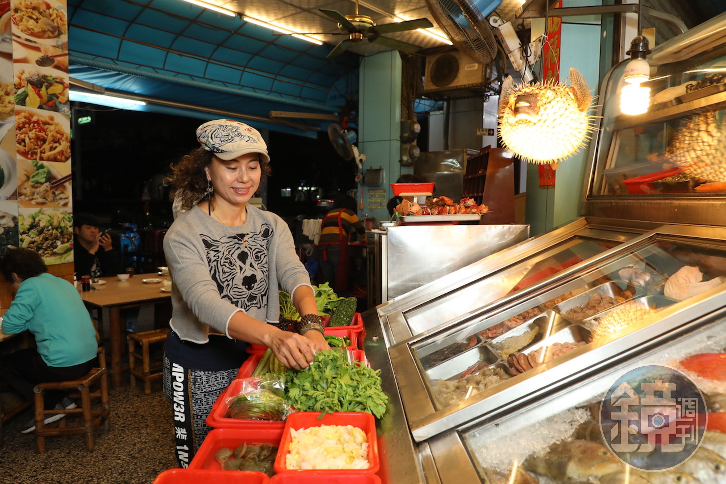 「海味澎湖活海產」每天傍晚起點亮招牌燈，老闆王雪燕在檯子擺滿澎湖魚貝和蔬菜。