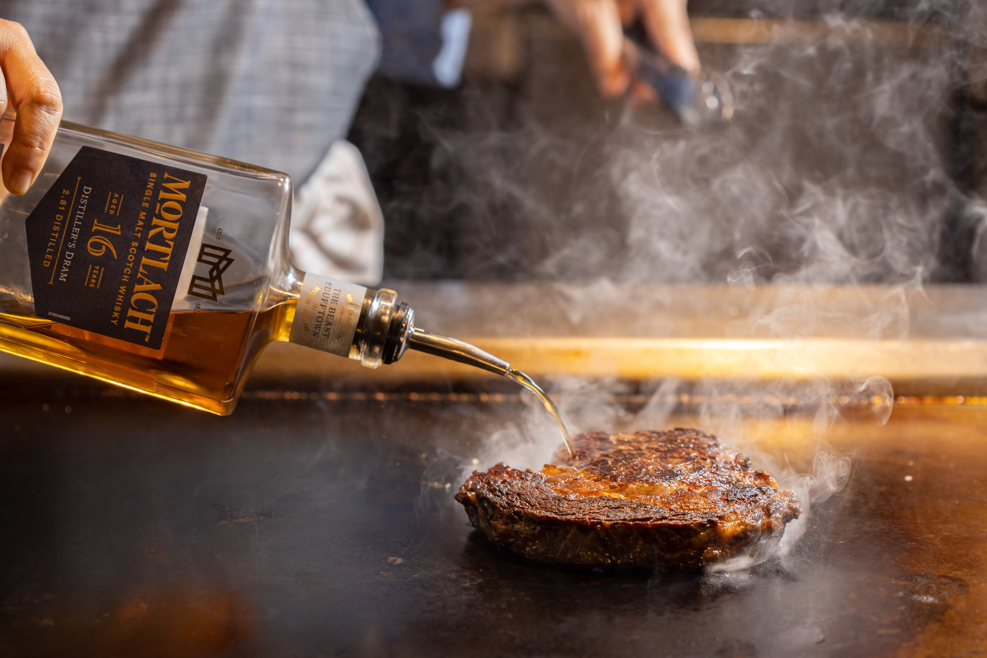 M5和牛肋眼先以鐵板煎，再上炭烤架，最後在鐵板上嗆「慕赫2.81 16年單一麥芽威士忌」。