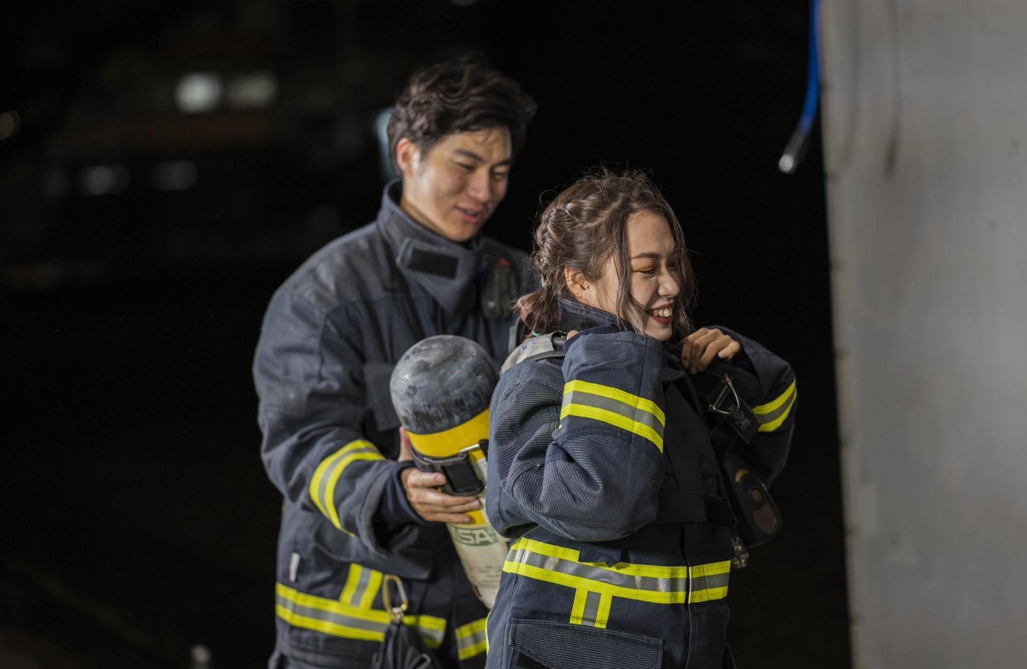 浪LIVE女孩小葵（右）與在林嘉楷教官（左）協助下挑戰90秒快速著裝，從消防頭套、消防鞋、消防褲到消防衣，背起重達十多公斤的氣瓶，再戴上消防面罩、消防頭盔和手套，每一樣都必須穿戴確實。（浪live提供