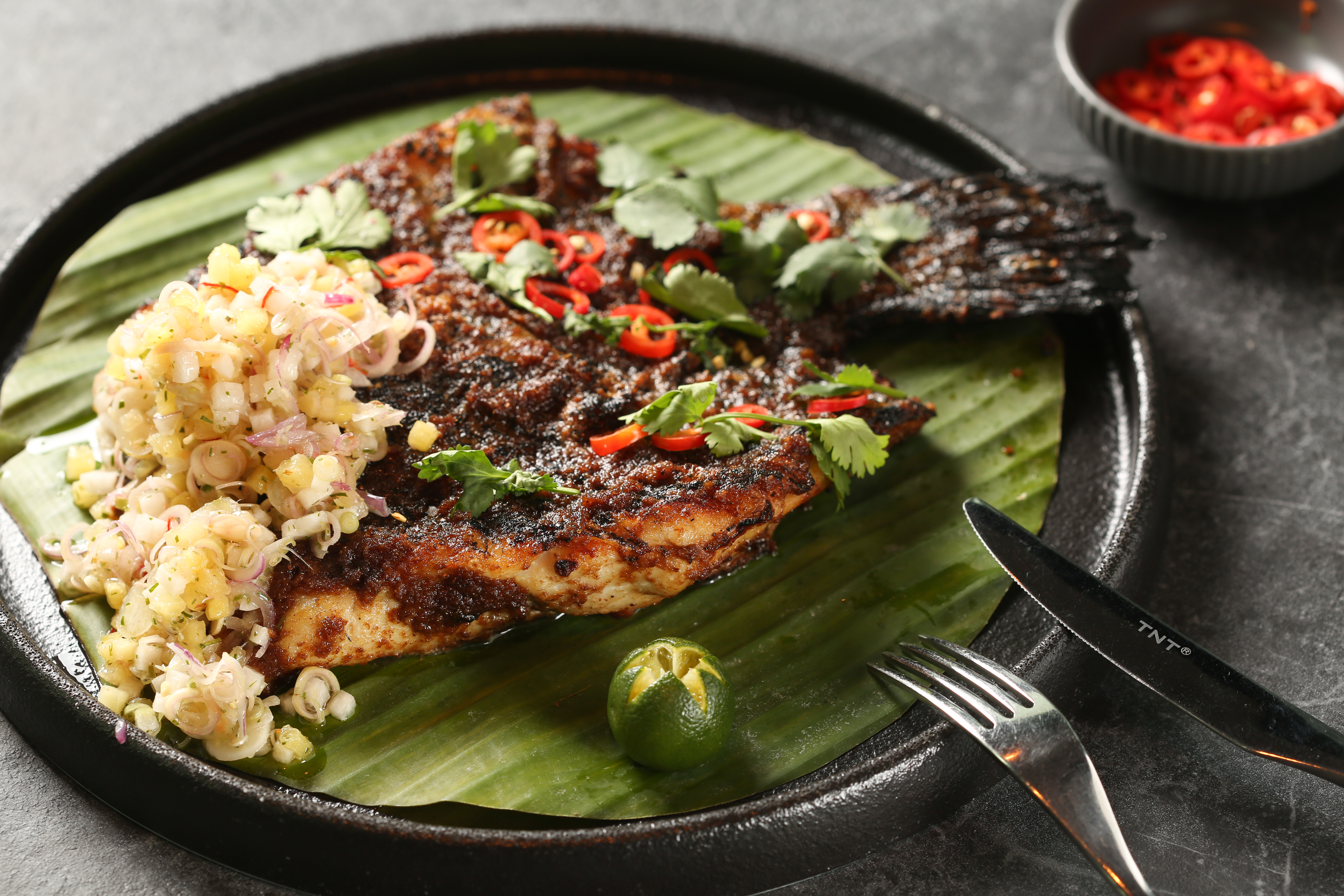 「炭烤參巴石斑魚」的參巴醬改良自CÉ LA VI新加坡總部的食譜，塗上醬料炭烤的魚肉外香內嫩。（1,680元／份）
