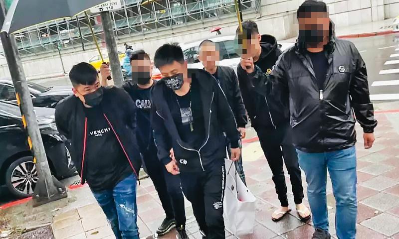 北投媽祖文化協會上月遭人開槍,楊姓(左3)及郭姓(左1)嫌犯搭乘小弟駕駛的名車赴警局投案,並由小弟撐傘護送,高調舉止引發議論。(翻攝畫面)
