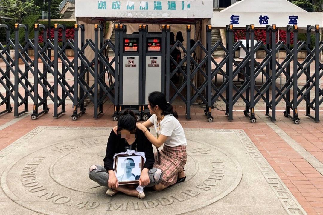 林姓學生母親坐在校門口要求校方給真相。(翻攝微博)