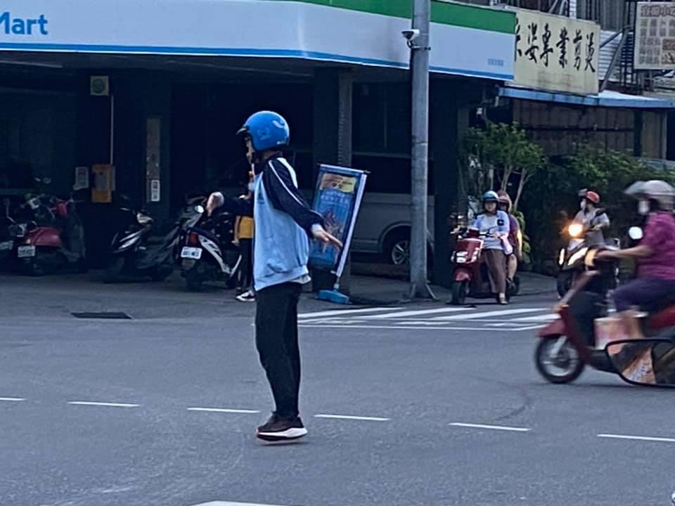 男學生頭戴安全帽,站在路口中央指揮車輛通行。(翻攝自花蓮同鄉會)