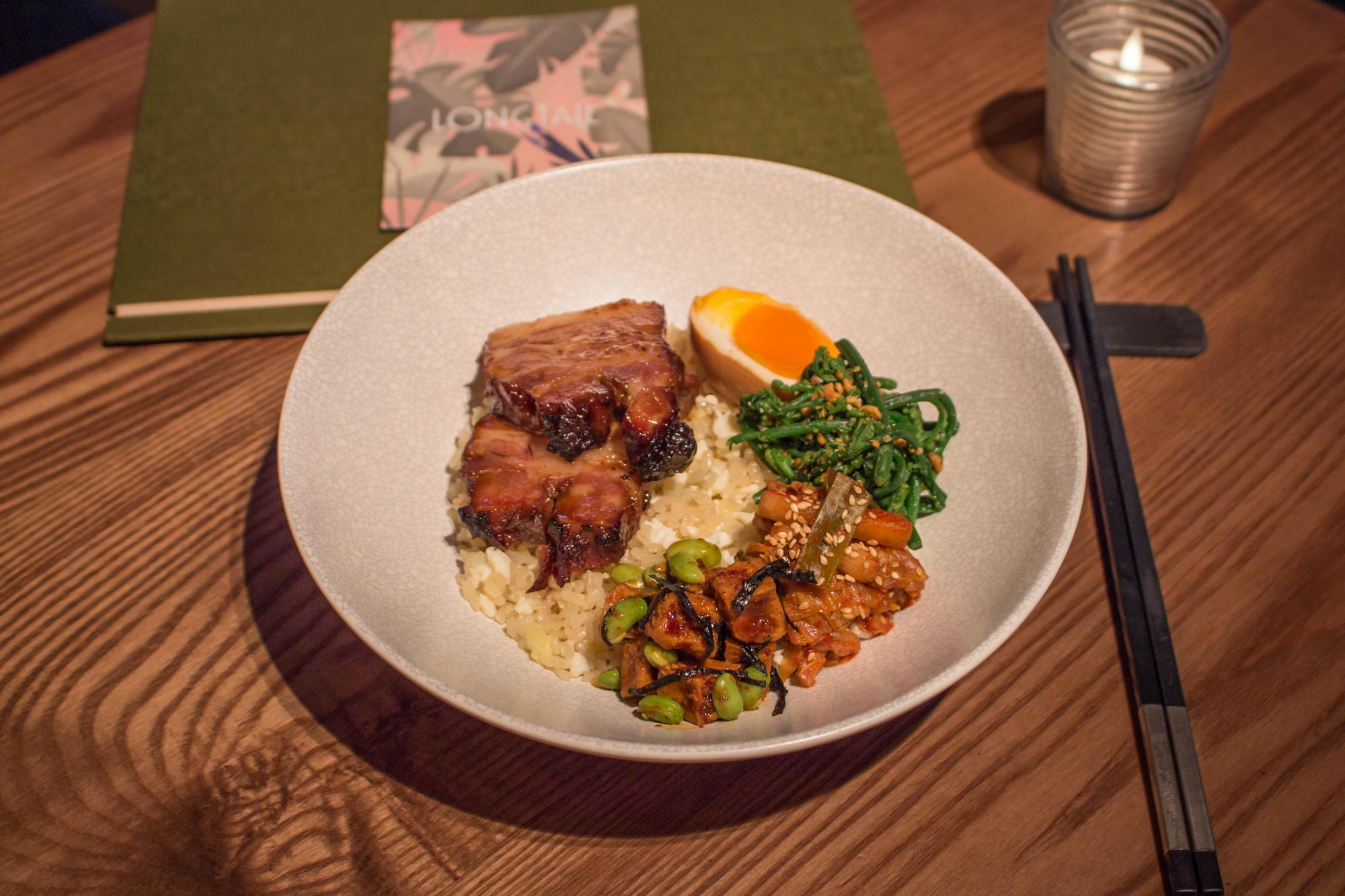 「叉燒飯」豬五花費心醃製再慢烤上色,米飯先以昆布高湯蒸煮,再拌炒蛋白,呈現道地港式風味,搭配茶香溏心蛋、3種配菜。(320元/個,LONGTAIL提供)