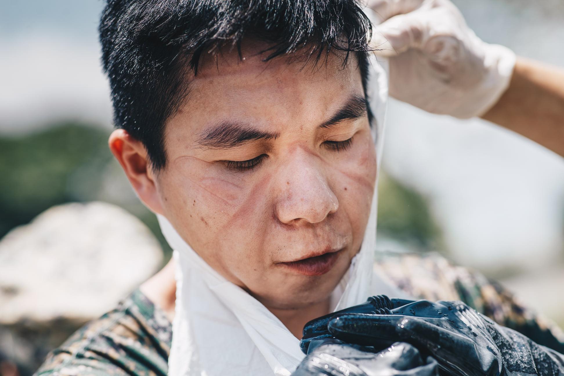 化學兵身穿悶熱的防護衣努力清消足跡,臉上被口罩壓出印痕。(軍聞社提供)
