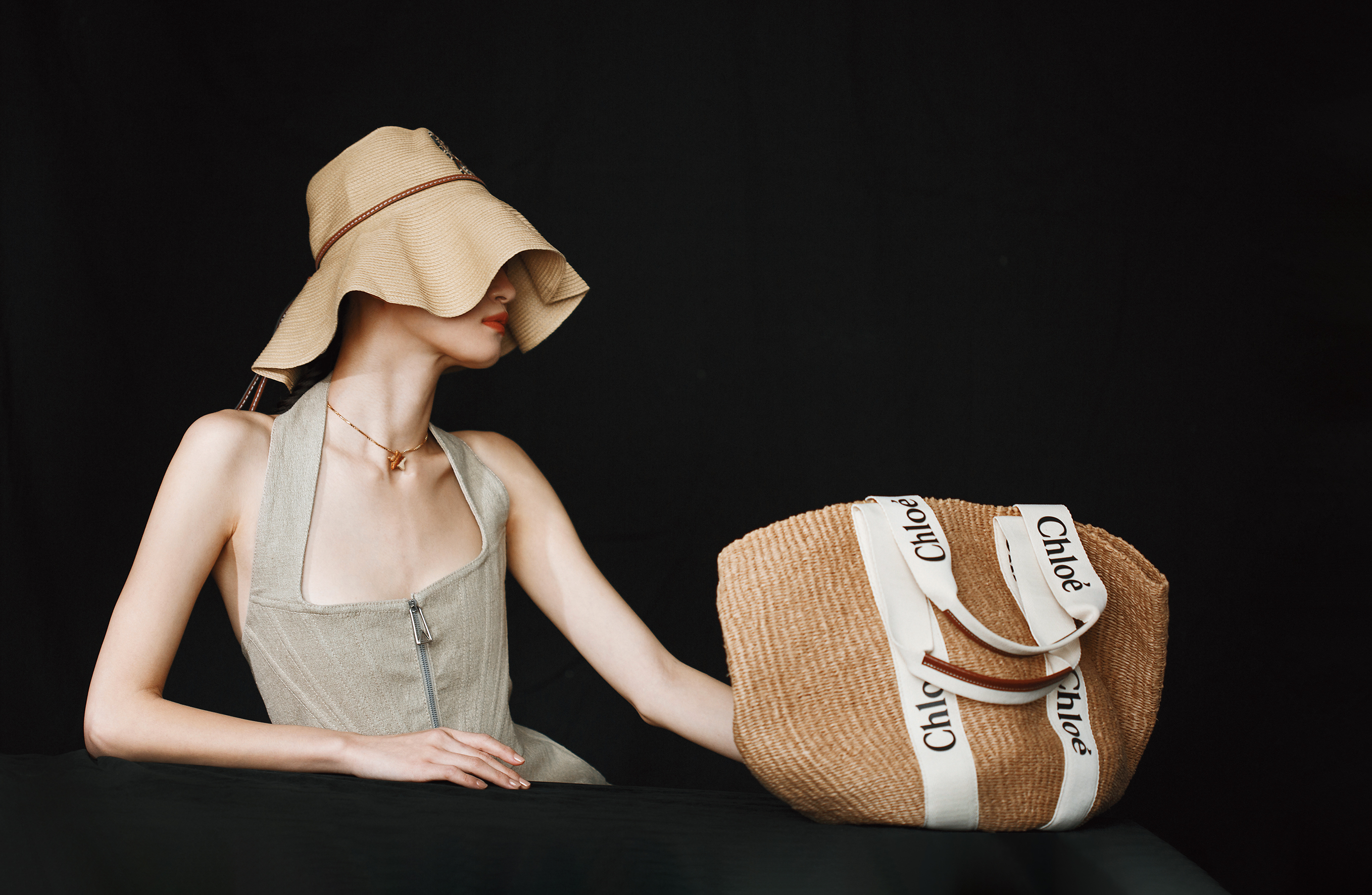 Woody編織托特包 NT$21,300 by Chloé；亞麻馬甲腰線洋裝 NT$100,100 by BOTTEGA VENETA；棕櫚葉寬簷草帽 NT$18,000 by LOEWE；星星造型碧玉純銀鍍金項鍊 NT$26,900 by BOTTEGA VENETA。