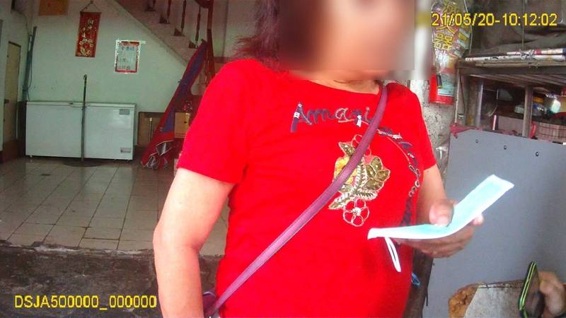楊姓婦人手中拿著警察送的口罩，就是拒絕戴上，隨後還用糟蹋人的態度，將口罩棄置地上。（市府提供）