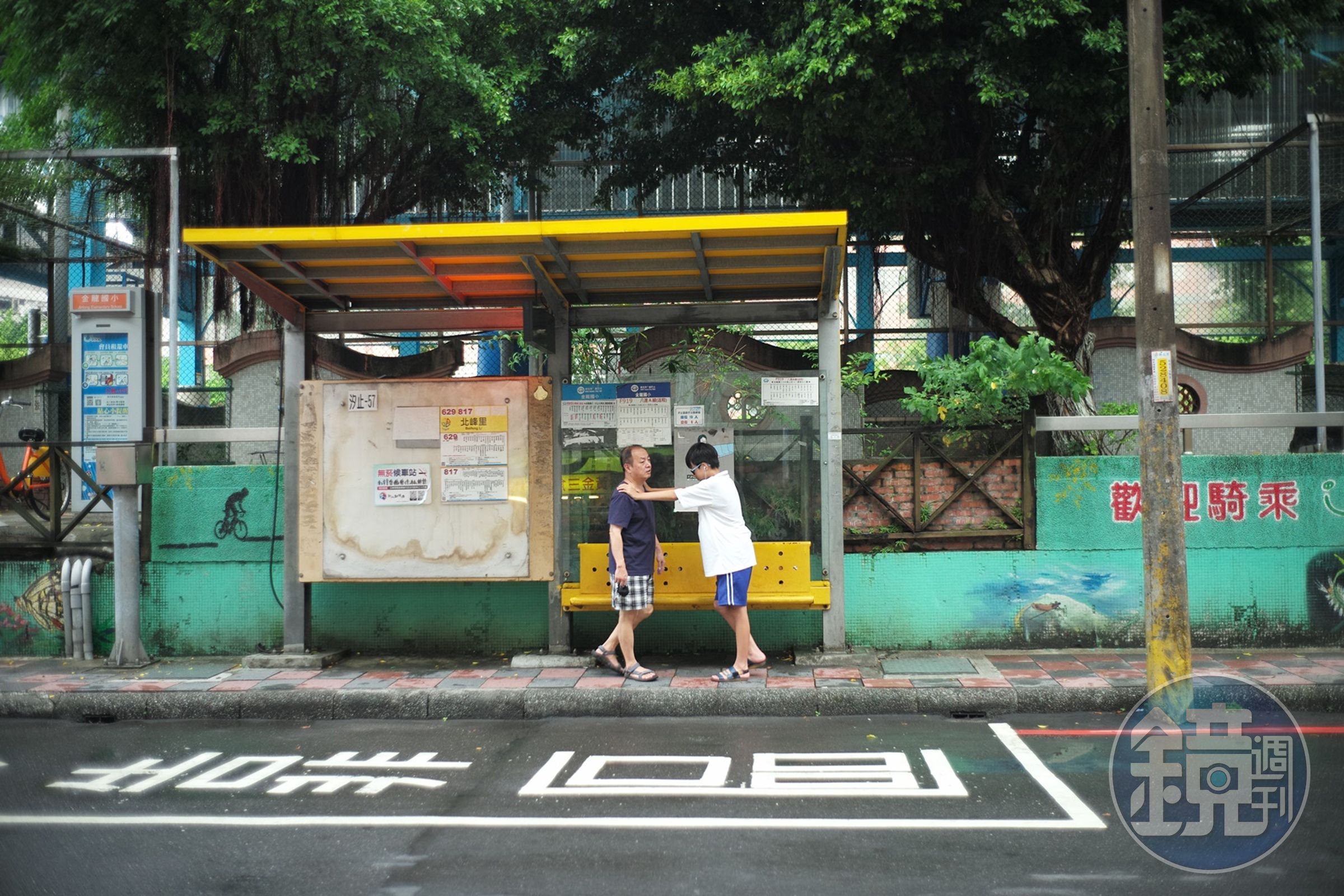 在公車站一起等車的父子。