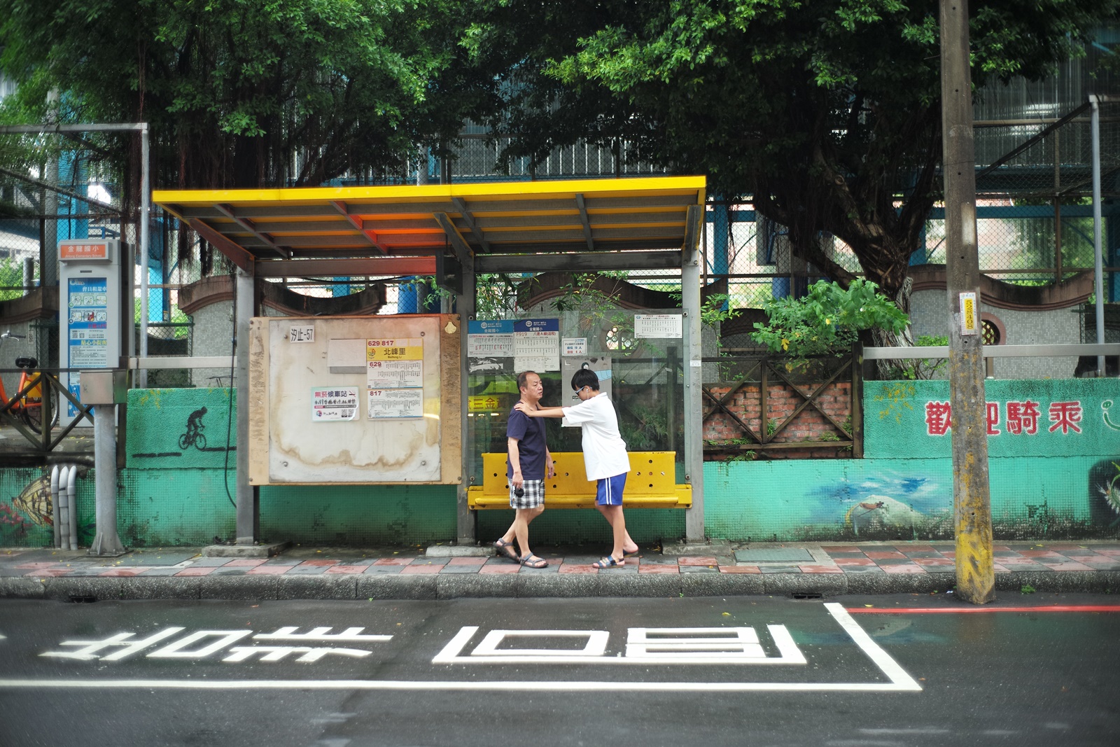 在公車站一起等車的父子。