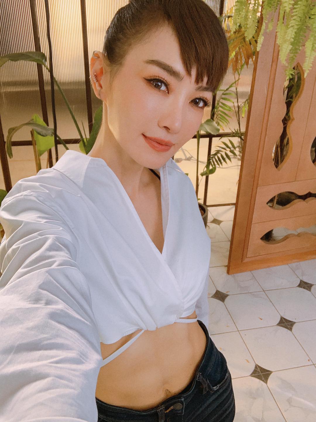 謝金燕上半身穿短版白襯衫、下半身搭配貼身牛仔褲，並露出腰部的健美腹肌。（翻攝自謝金燕臉書）