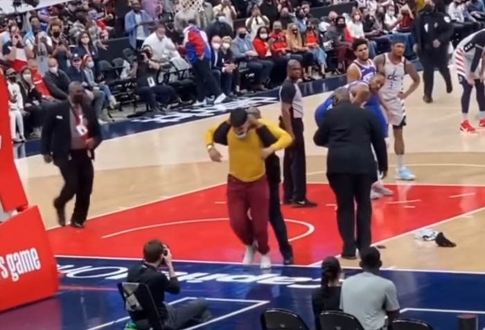 華盛頓巫師與費城76人的比賽中，一名身穿黃色衣服的球迷「失控」衝進場內，遭到保安壓制驅離。（翻攝自TakingFlight Sports YouTube頻道）