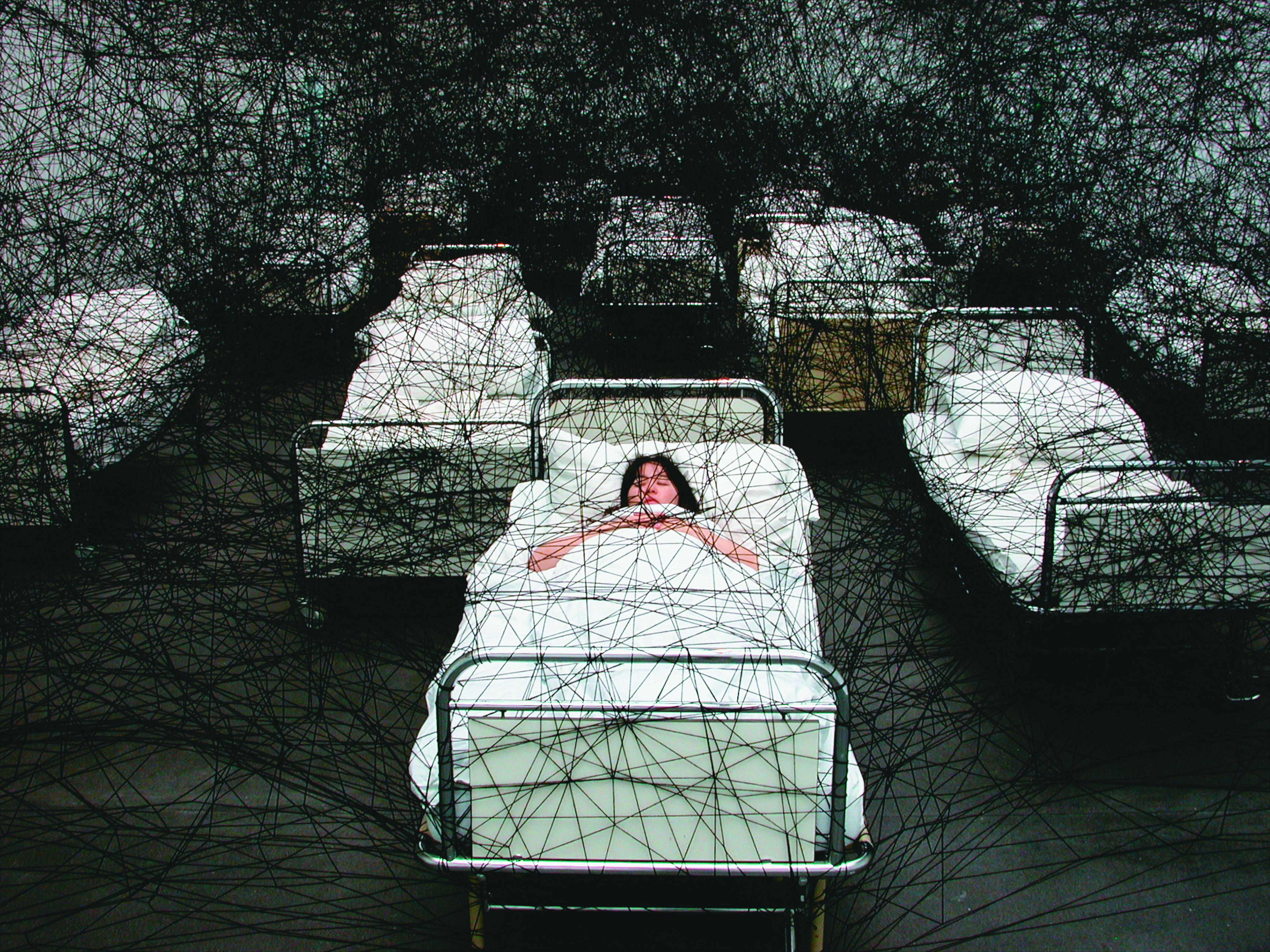 塩田千春結合裝置與行為的作品〈在沉睡中〉（During Sleep），她躺在床上睡覺，床則象徵了人生的起點與終點。（塩田千春提供）