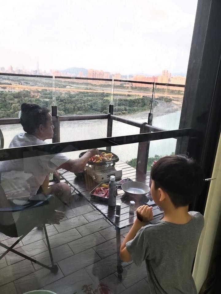 陳仙梅側拍攝影師老公躲在陽台燒烤模樣。(翻攝自陳仙梅臉書)