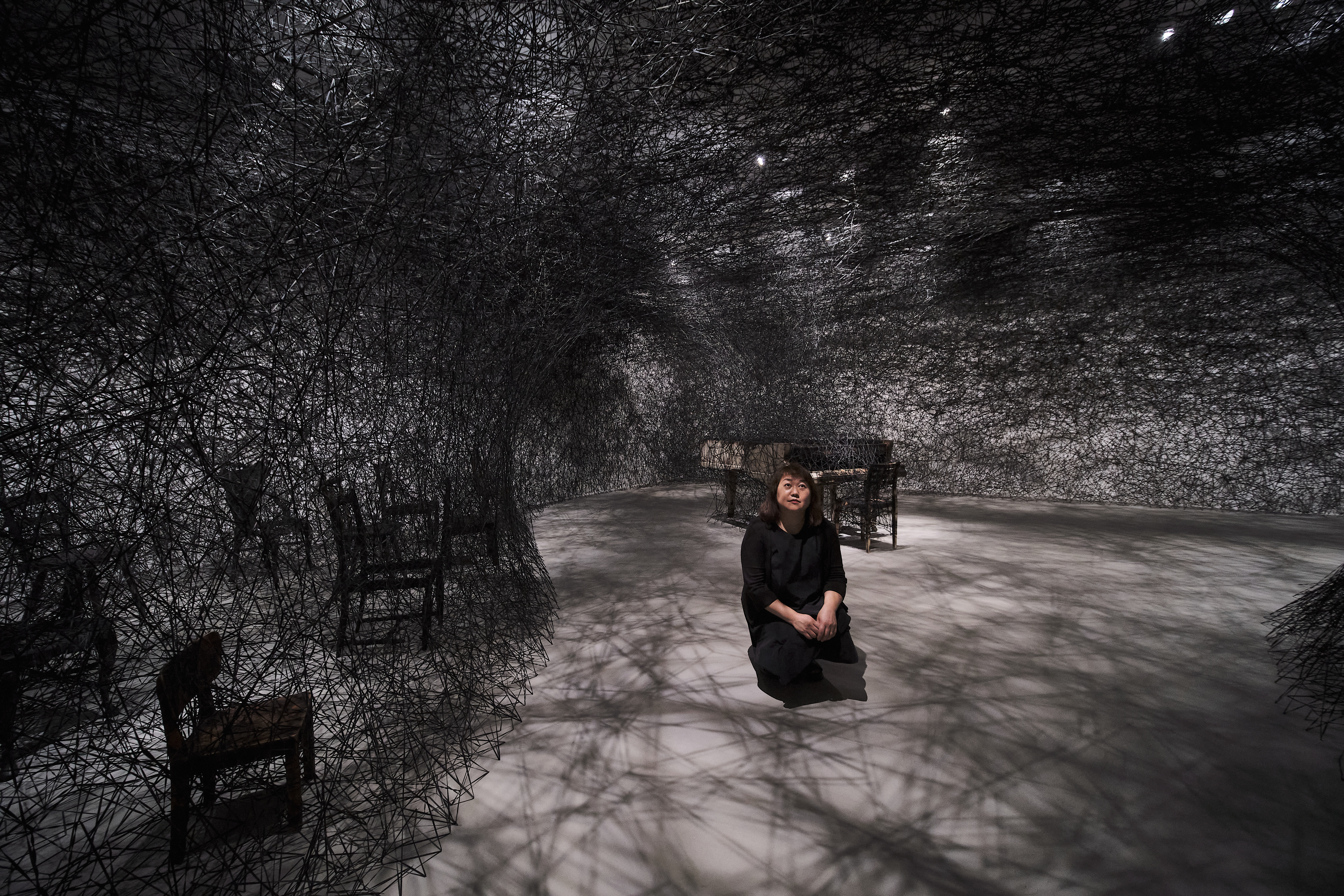 塩田千春4月底特地從柏林飛到台北布展。圖為她以黑色織線、燒焦鋼琴與椅子製作的裝置〈靜默中〉（In Silence）。