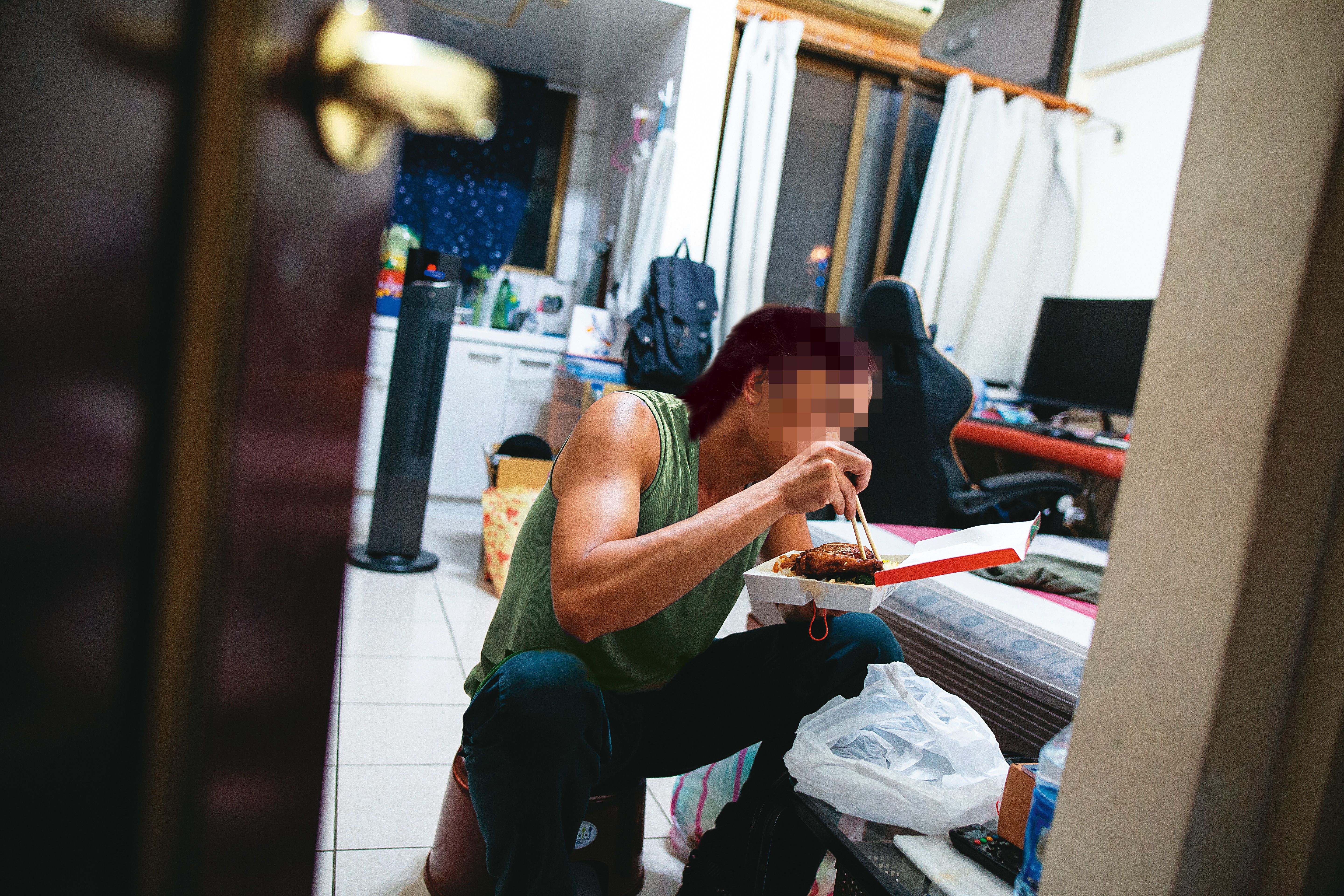 晚上9點，阿康回到家，吃著冷掉的便當，儘管早已累到失去胃口，仍努力把雞腿吞下肚。（圖中人物已經變裝處理）