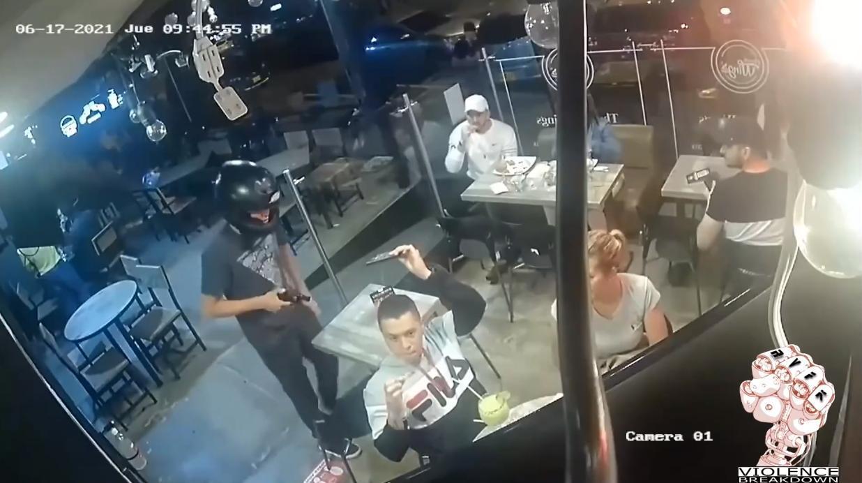 男子一邊啃雞翅，一邊把自己的手機交給搶匪。（翻攝自YouTube）