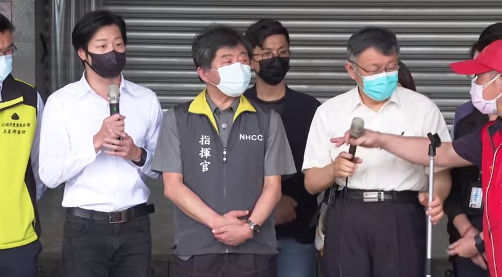 環南市場自治會會長（紅衣男）搶過柯文哲手中的麥克風開罵。（翻攝疾管署Youtube）