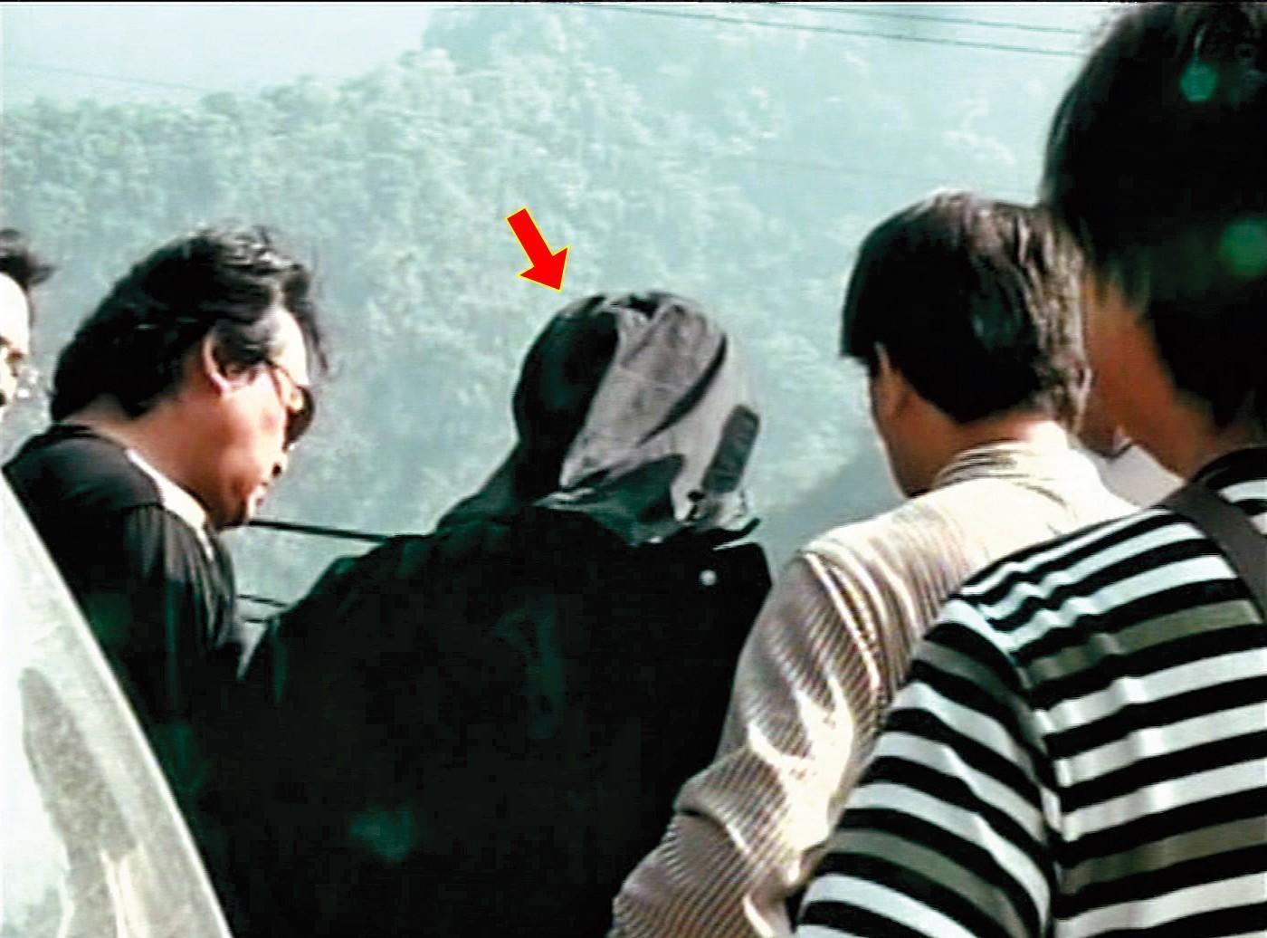 警方押解何男(箭頭者)前往南投丹大林道棄屍山谷,尋找死者遺體。(東森新聞提供)