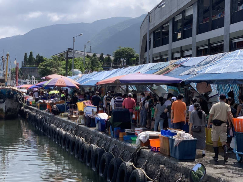 宜蘭頭城鎮大溪漁港週末人潮再度爆滿，讓做生意的魚販也不禁擔心成為防疫破口。（林麗提供）