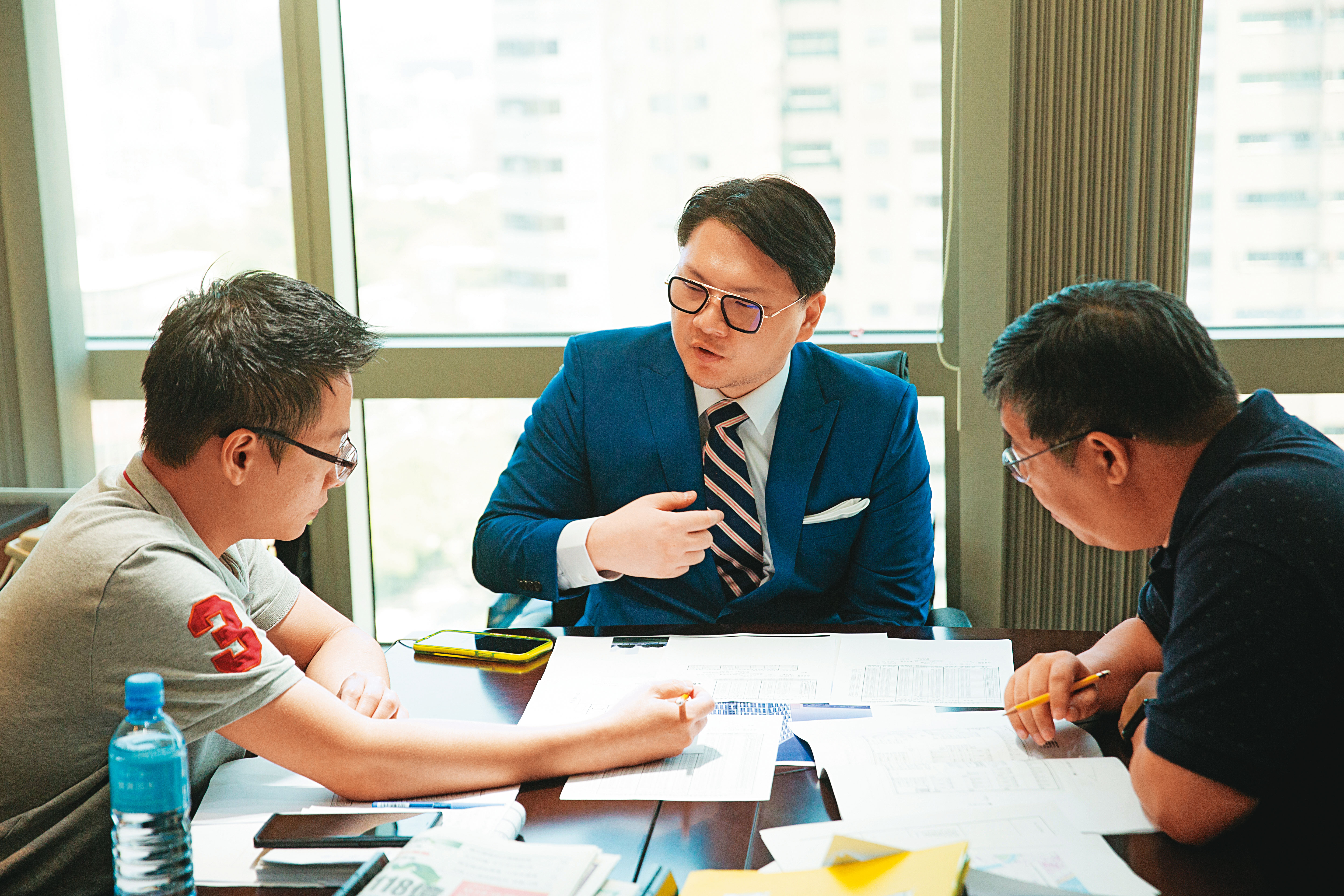 採訪當天，鍾育霖（中）正在商談旗下建案規畫，不到40歲的他已經是一家百億集團操盤人。