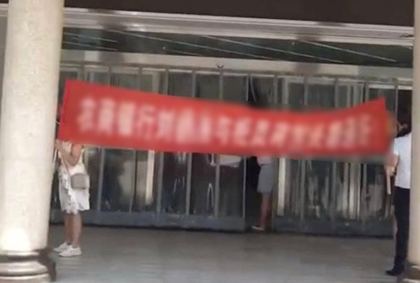 中國大陸一名人妻發現丈夫出軌，在銀行門口拉起紅布條。（翻攝自《極目新聞》微博）