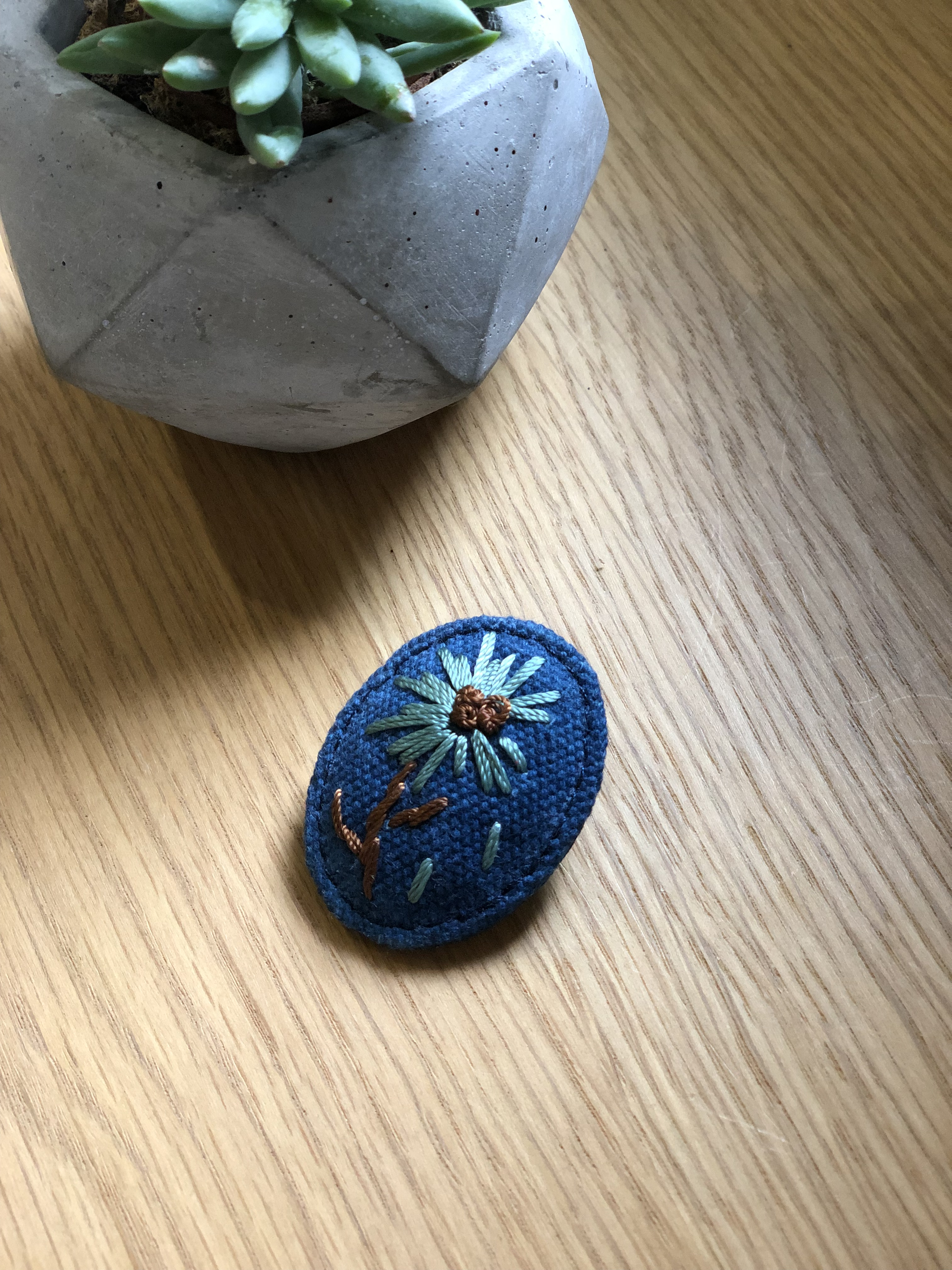 以寥寥幾針點出花草模樣的胸針，別在衣領上頗收畫龍點睛之效。