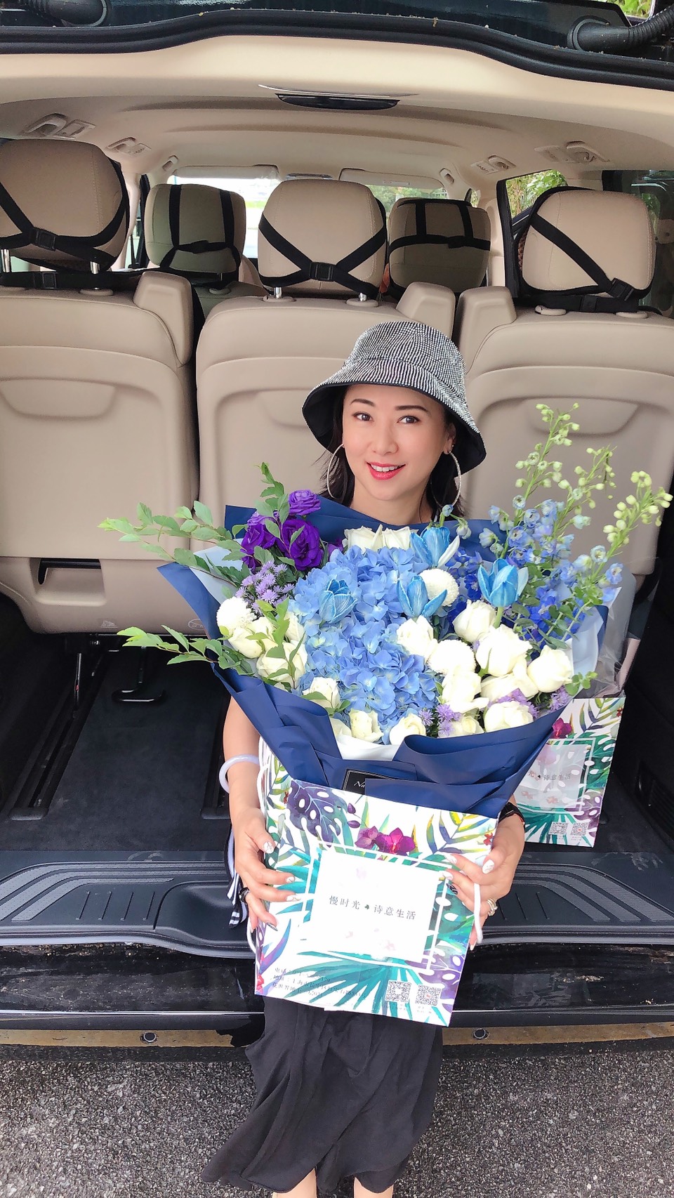 翁虹捧著兩束鮮花、坐著剛添購的休旅車，去迎接結束隔離的老公女兒。（翁虹提供）