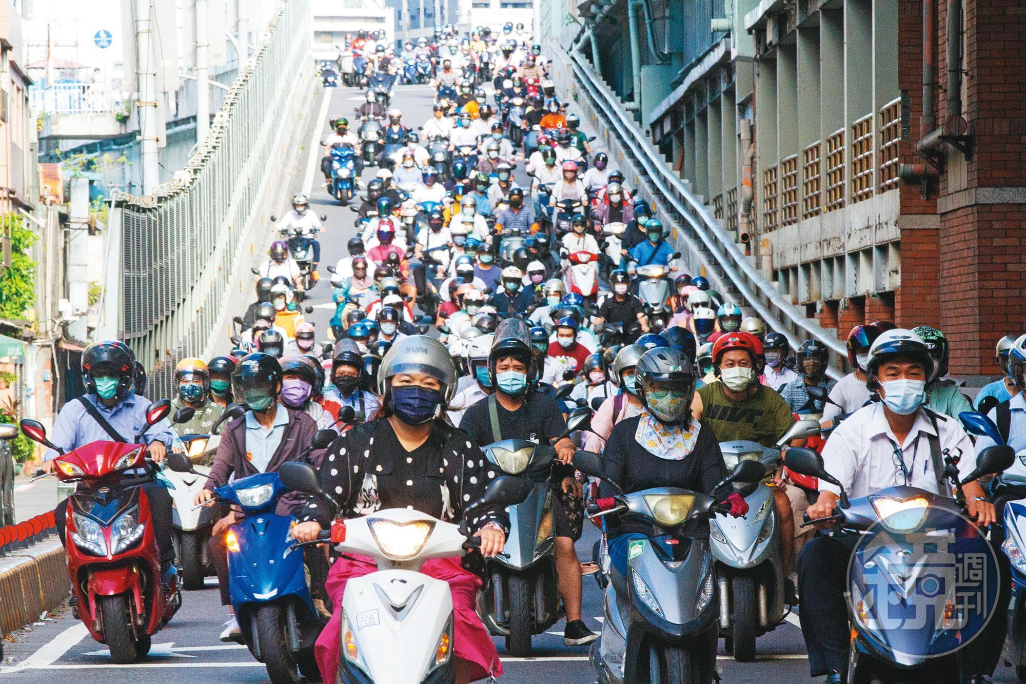 疫情期間,往返雙北的機車騎士緊緊戴上口罩。隨著警戒有望降級,政府研議相關配套措施,而口罩仍被視為是防疫最後防線。