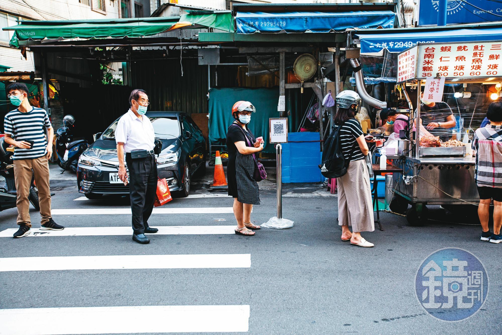 在新北市樂華夜市,民眾排隊採買依舊保持社交距離。即便月底降級,維持社交距離仍是防疫重點。