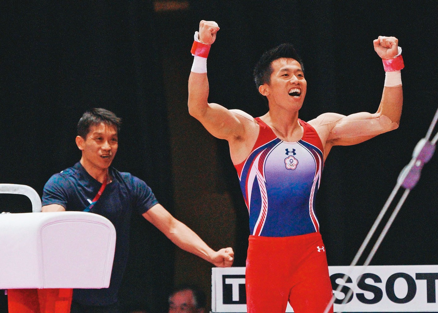 2018年亞運李智凱（前）奪得台灣體操首金，完美落地後教練林育信（後）即上前擁抱祝賀。（翻攝自中華奧委會官網）