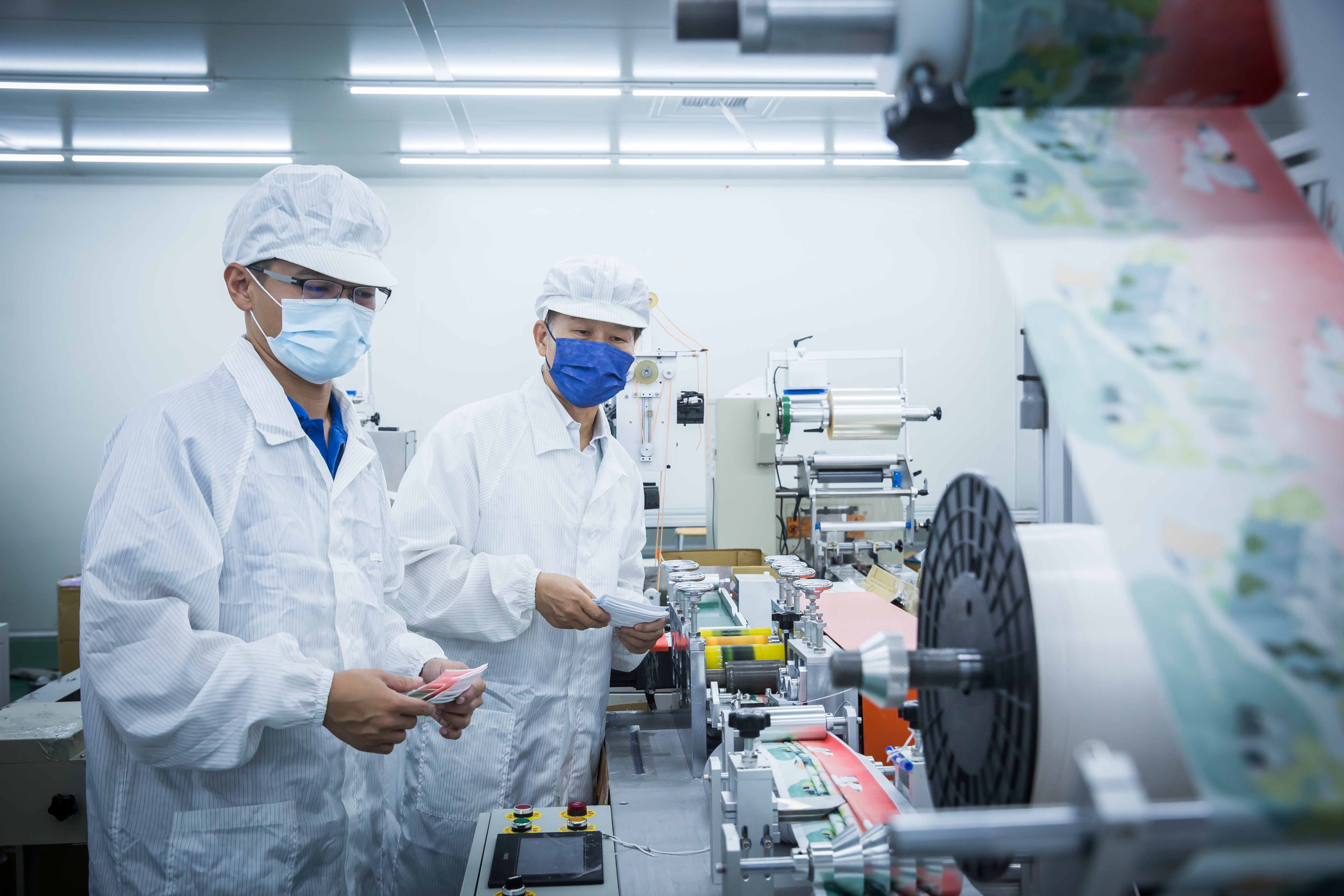 去年疫情爆發，周文東（左）決定將原本供應面膜不織布的產線，改為生產熔噴不織布，日產70萬片口罩。右為在公司培訓、擔任特助的兒子周紹華。