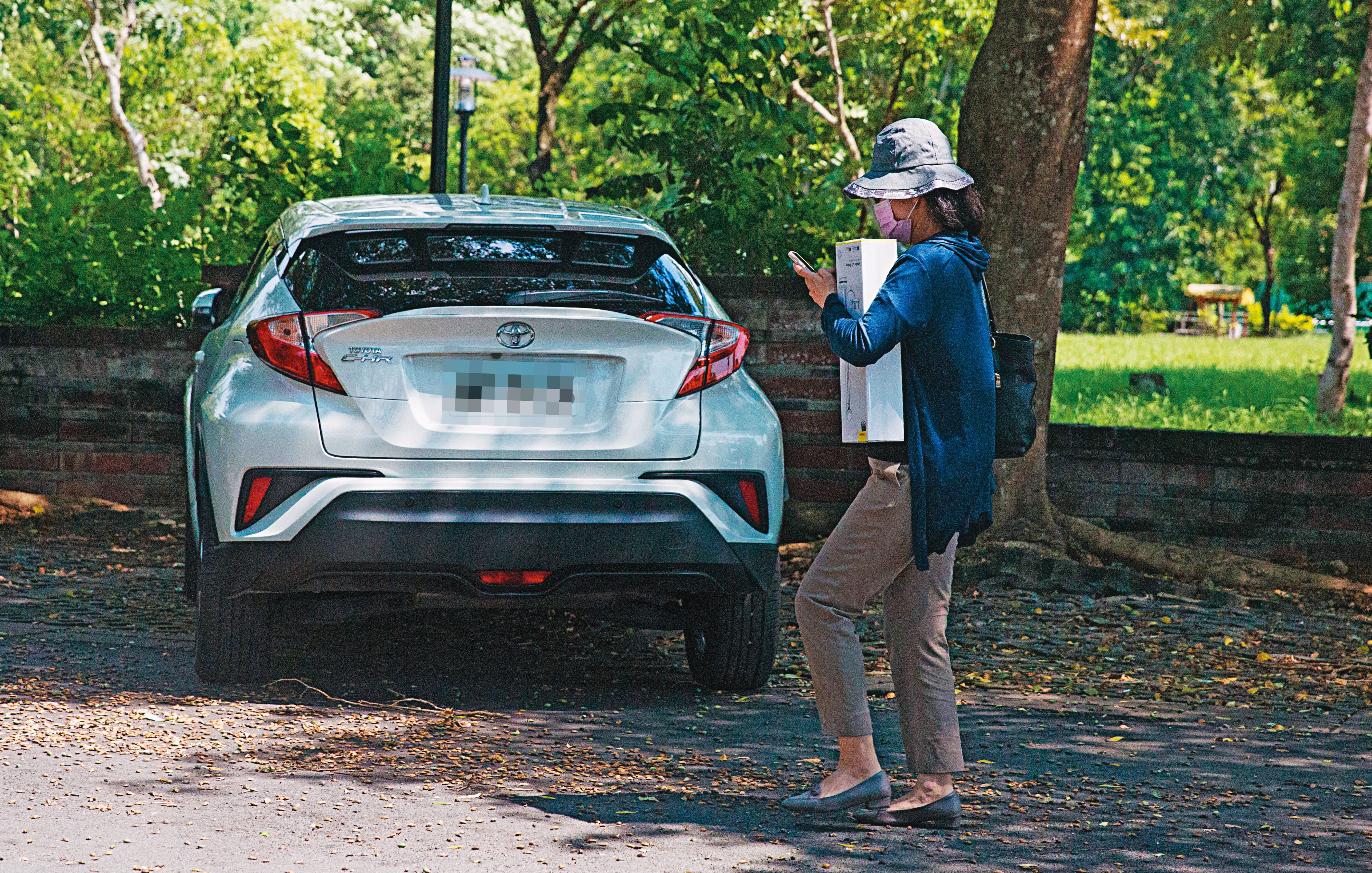 ↑H女拿著1個白色禮盒，走回自己的白車旁，準備開車回家。